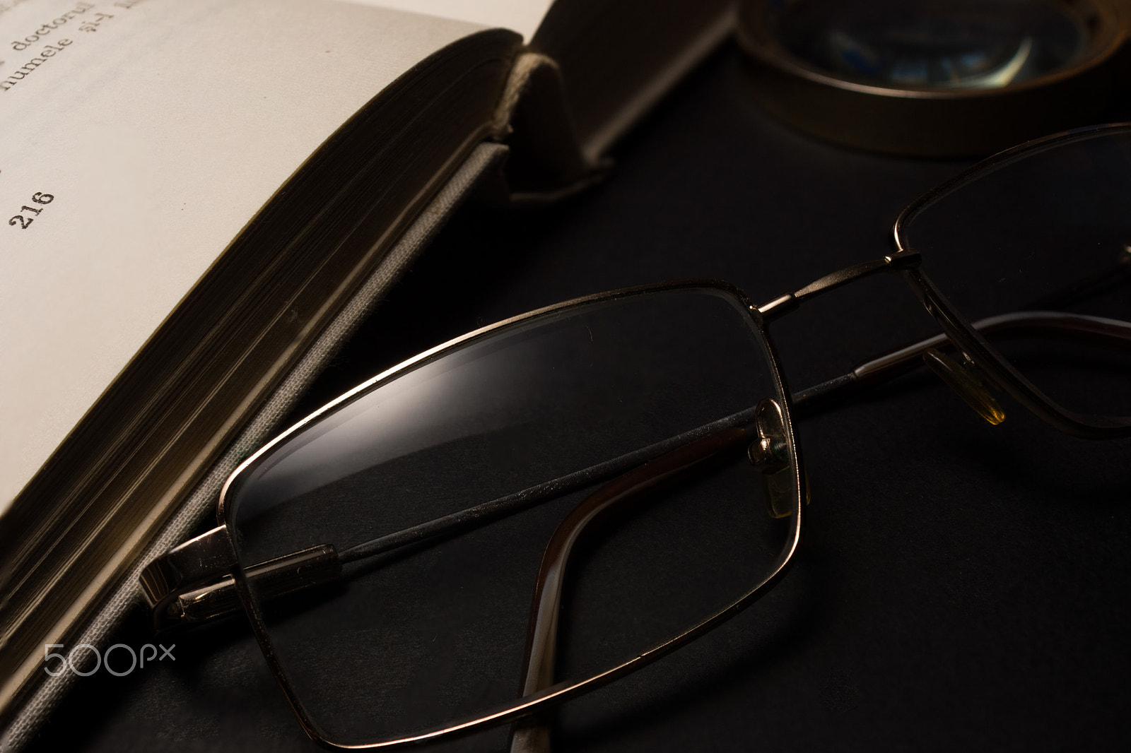 Sony SLT-A77 + Minolta AF 28-85mm F3.5-4.5 sample photo. Eyeglasses with magnifying glass on dark surface with books. photography