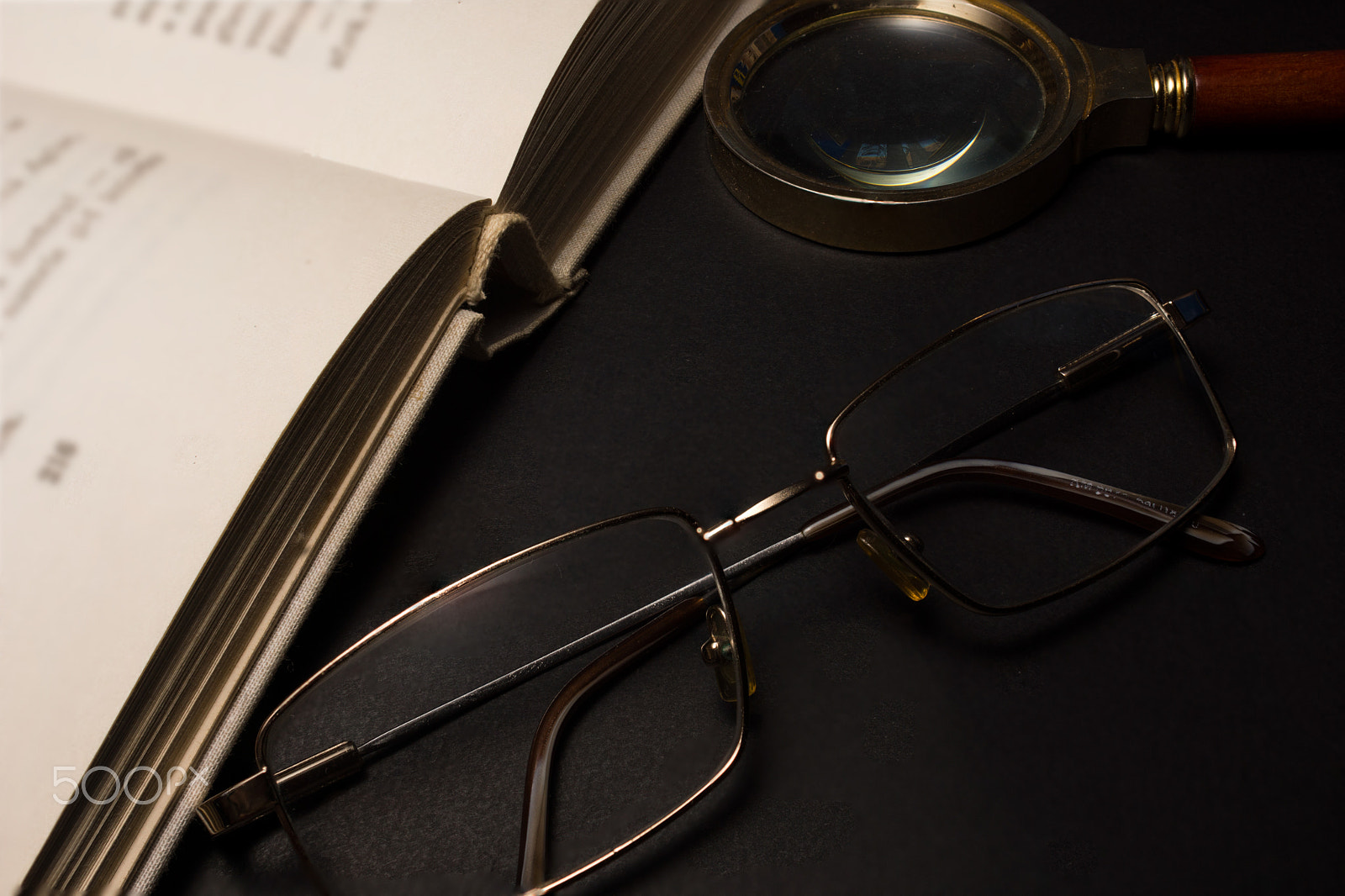Sony SLT-A77 + Minolta AF 28-85mm F3.5-4.5 sample photo. Eyeglasses with magnifying glass on dark surface with books. photography