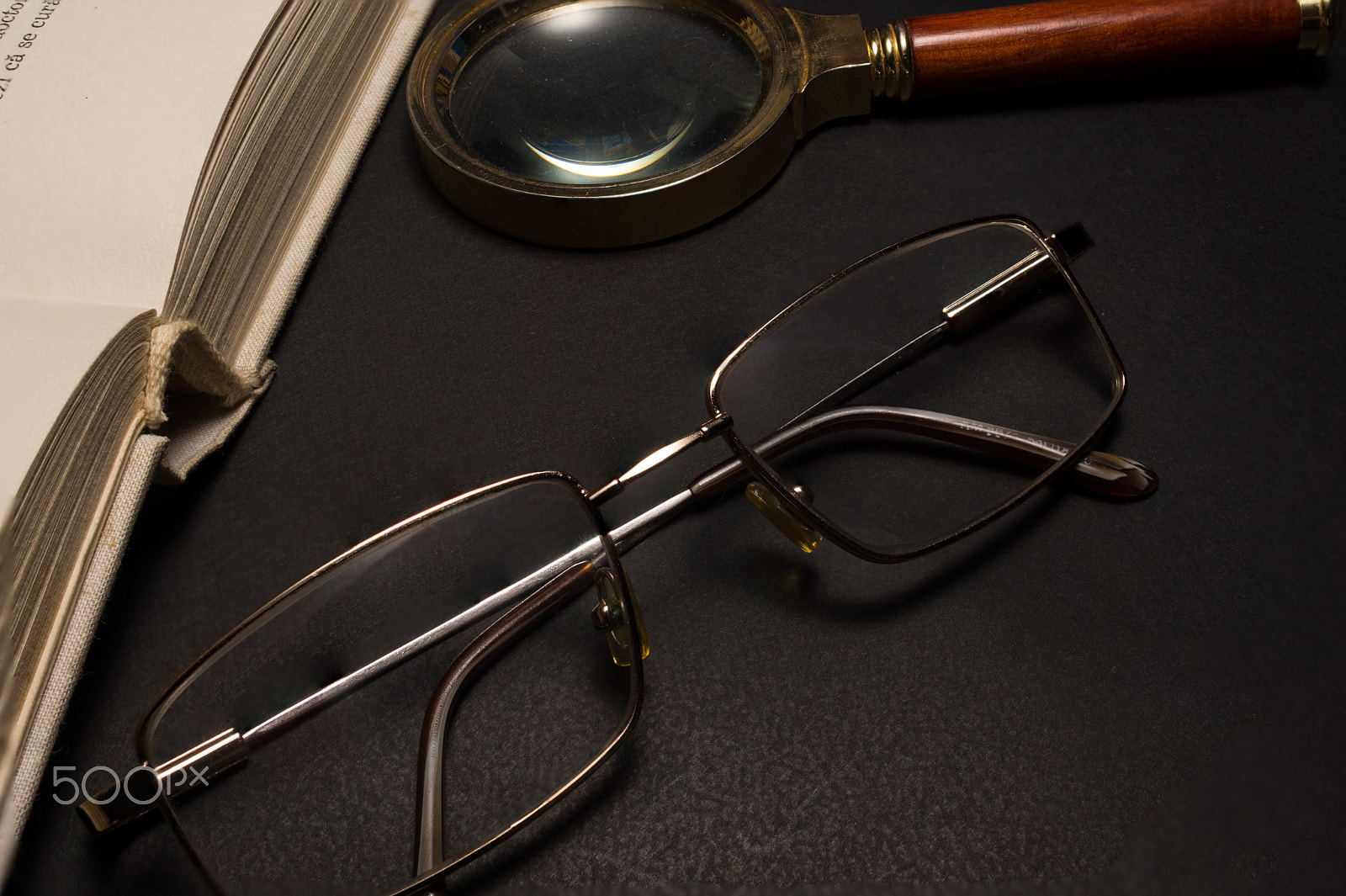 Sony SLT-A77 + Minolta AF 28-85mm F3.5-4.5 sample photo. Eyeglasses with magnifying glass on dark surface with books. photography