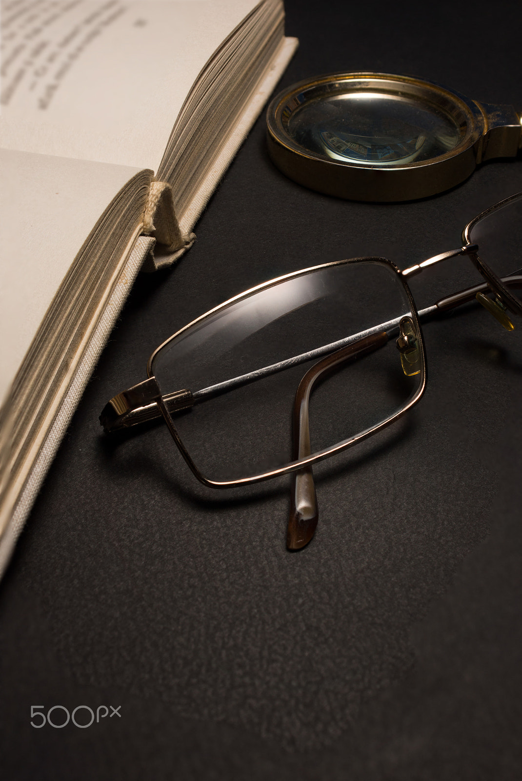 Sony SLT-A77 + Minolta AF 28-85mm F3.5-4.5 sample photo. Eyeglasses with magnifying glass on dark surface with books. photography