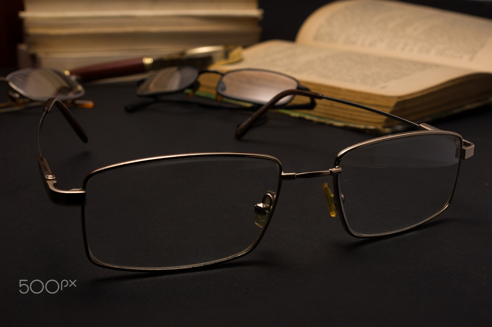 Sony SLT-A77 + Minolta AF 28-85mm F3.5-4.5 sample photo. Eyeglasses with magnifying glass on dark surface with books. photography