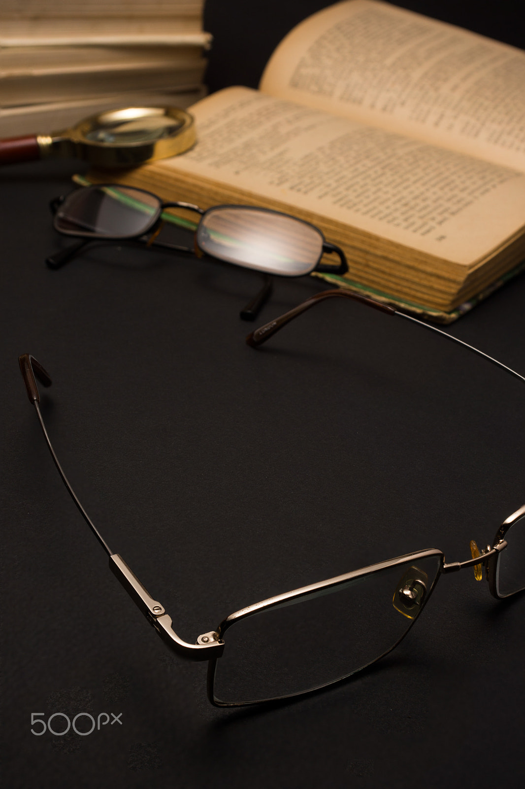 Sony SLT-A77 + Minolta AF 28-85mm F3.5-4.5 sample photo. Eyeglasses with magnifying glass on dark surface with books. photography