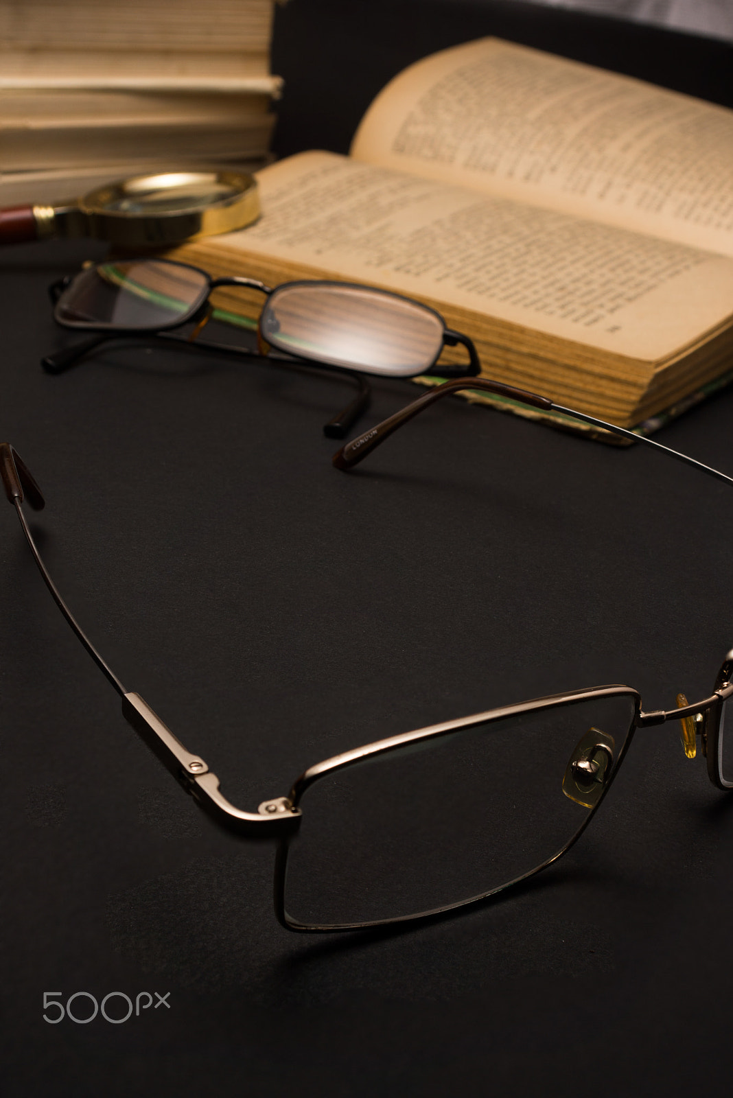 Sony SLT-A77 + Minolta AF 28-85mm F3.5-4.5 sample photo. Eyeglasses with magnifying glass on dark surface with books. photography