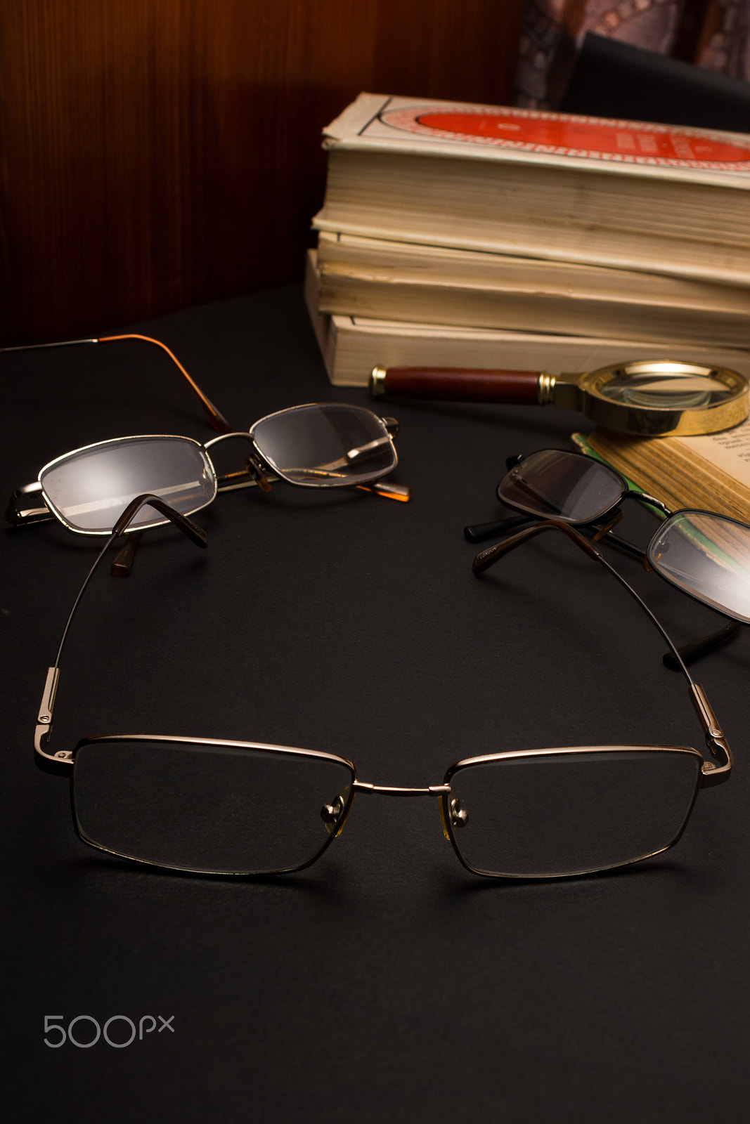 Sony SLT-A77 + Minolta AF 28-85mm F3.5-4.5 sample photo. Eyeglasses with magnifying glass on dark surface with books. photography
