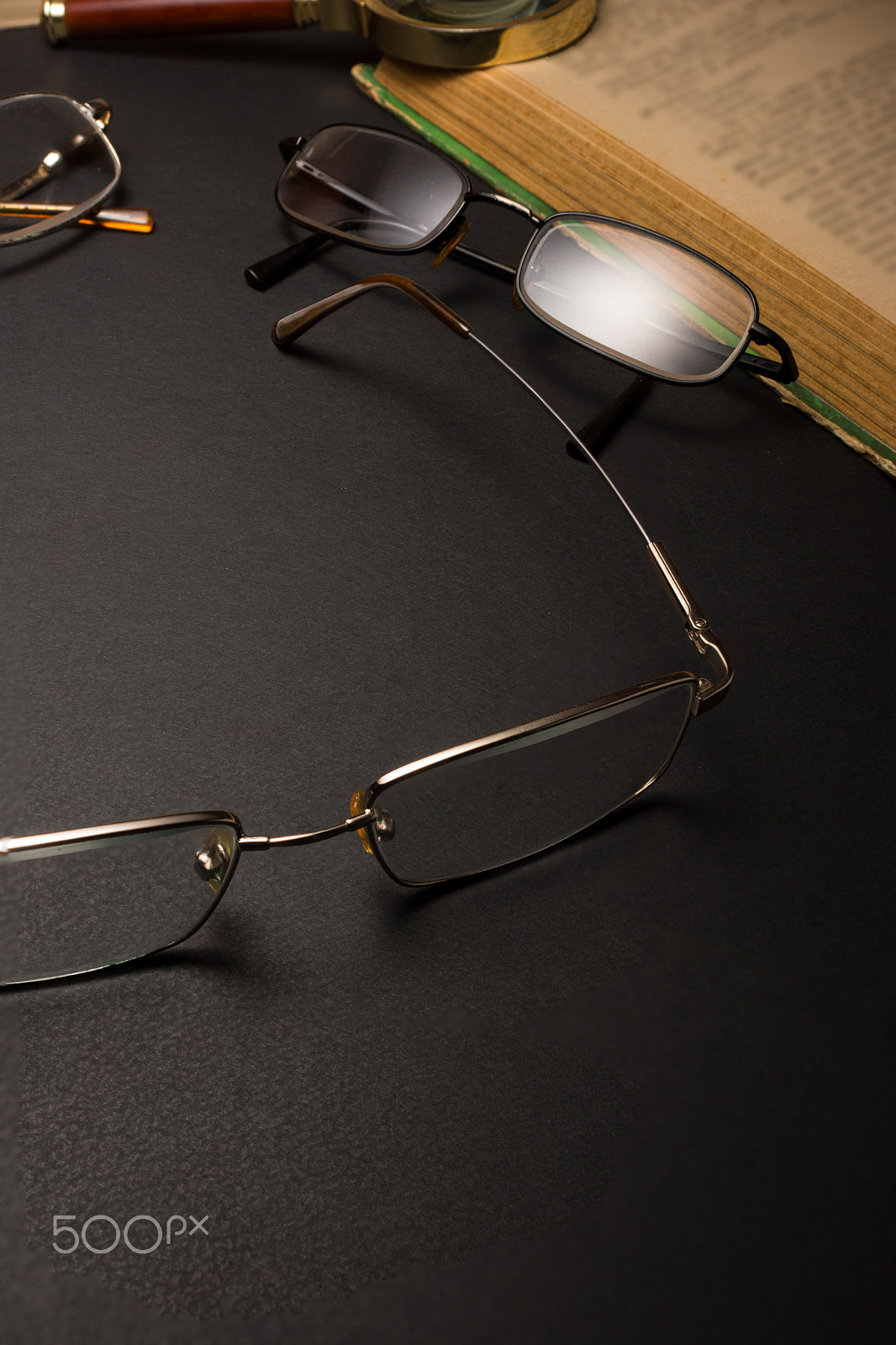 Sony SLT-A77 + Minolta AF 28-85mm F3.5-4.5 sample photo. Eyeglasses with magnifying glass on dark surface with books. photography