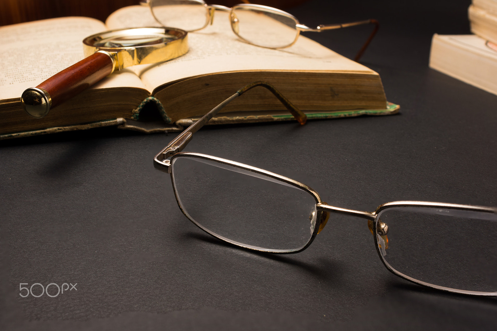 Sony SLT-A77 + Minolta AF 28-85mm F3.5-4.5 sample photo. Eyeglasses with magnifying glass on dark surface with books. photography