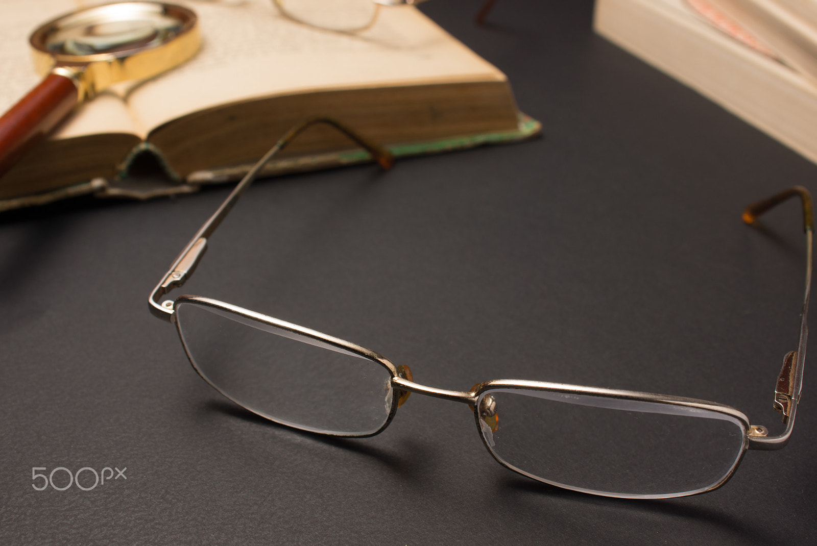 Sony SLT-A77 + Minolta AF 28-85mm F3.5-4.5 sample photo. Eyeglasses with magnifying glass on dark surface with books. photography