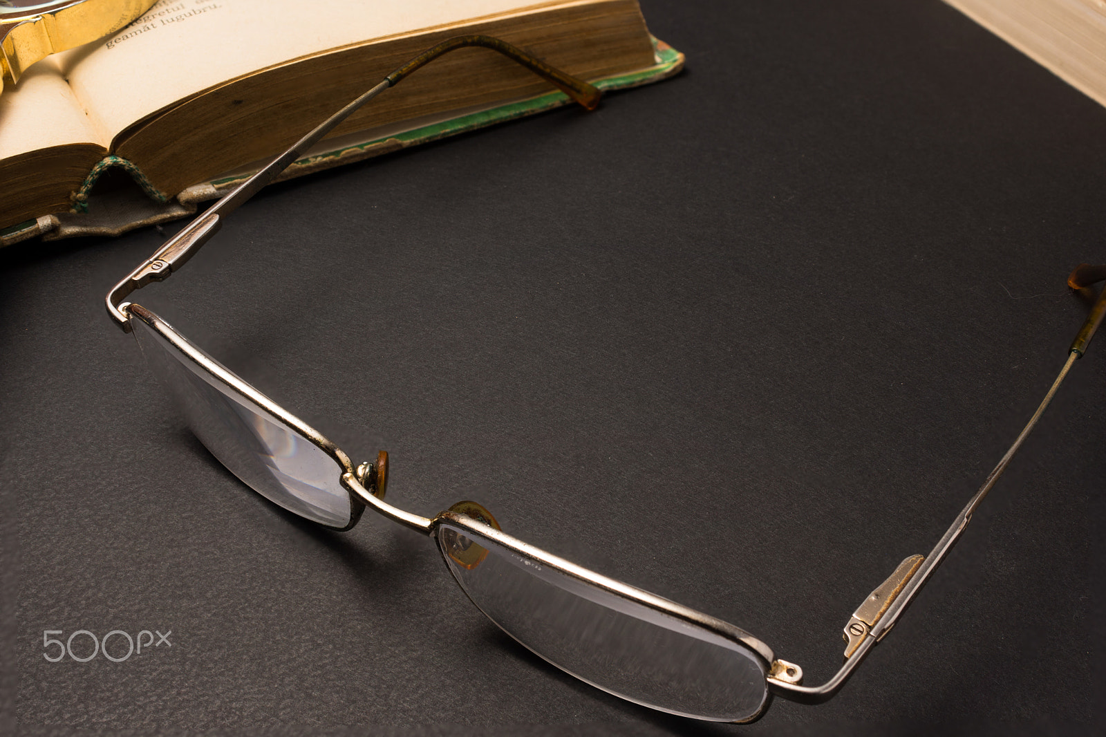 Sony SLT-A77 + Minolta AF 28-85mm F3.5-4.5 sample photo. Eyeglasses with magnifying glass on dark surface with books. photography