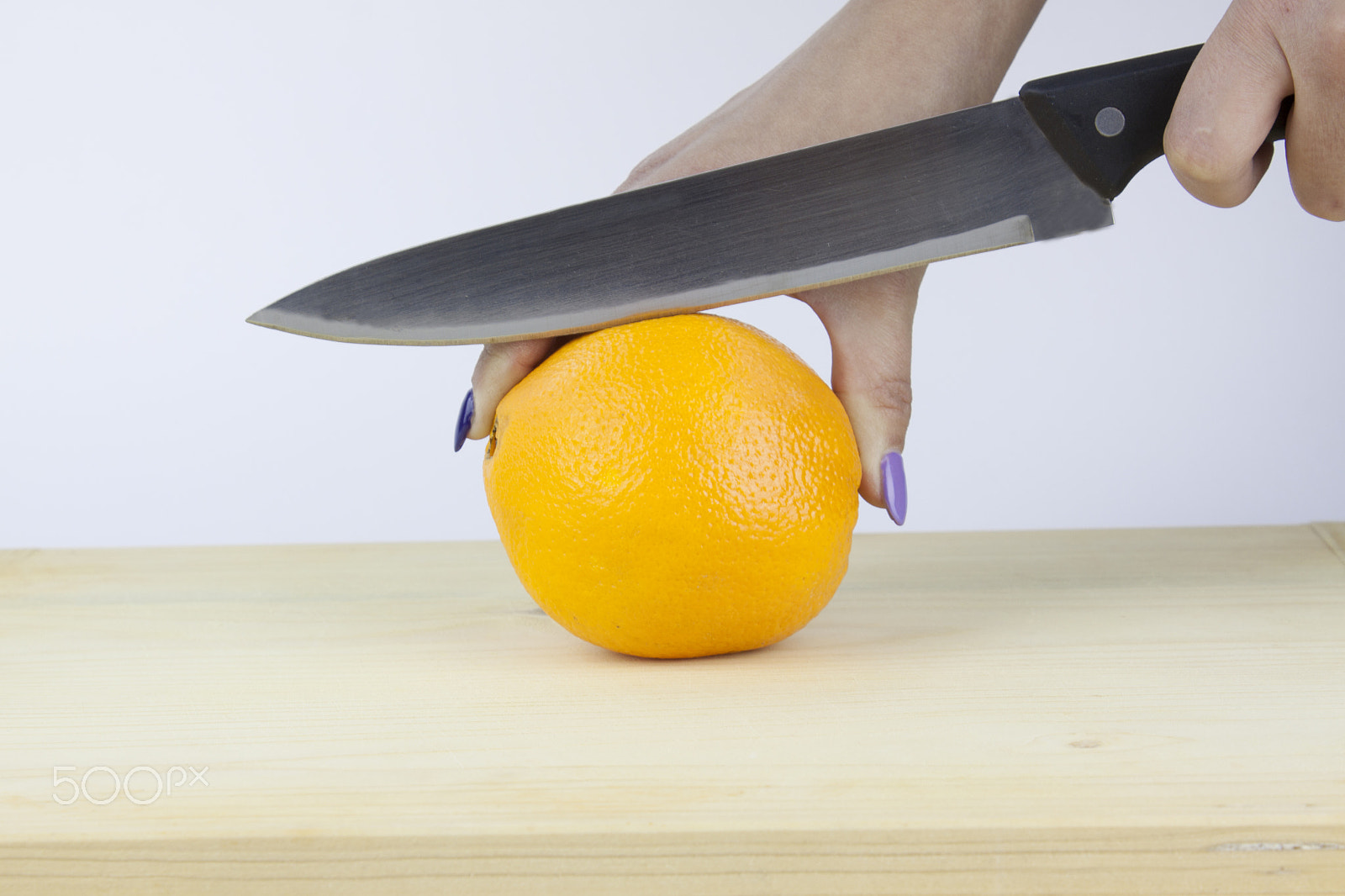 Canon EF-S 18-55mm F3.5-5.6 III sample photo. Hand cutting an orange on a wooden board photography