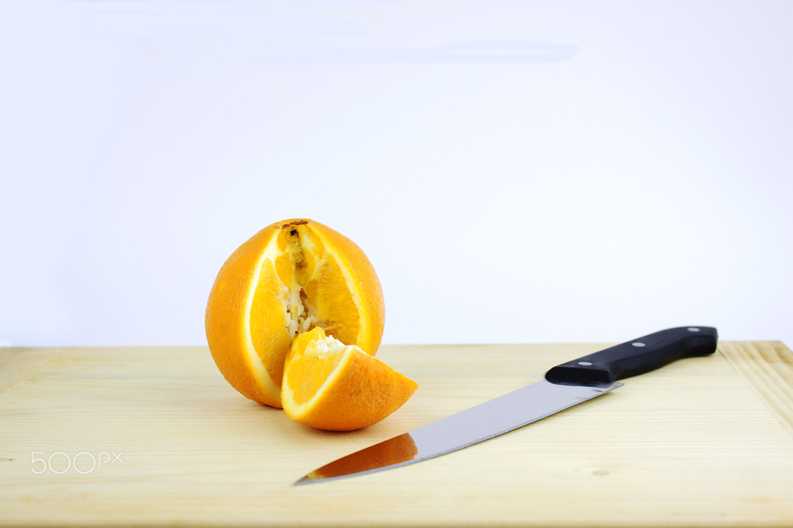 Canon EF-S 18-55mm F3.5-5.6 III sample photo. Cut orange on a wooden board near a knife photography