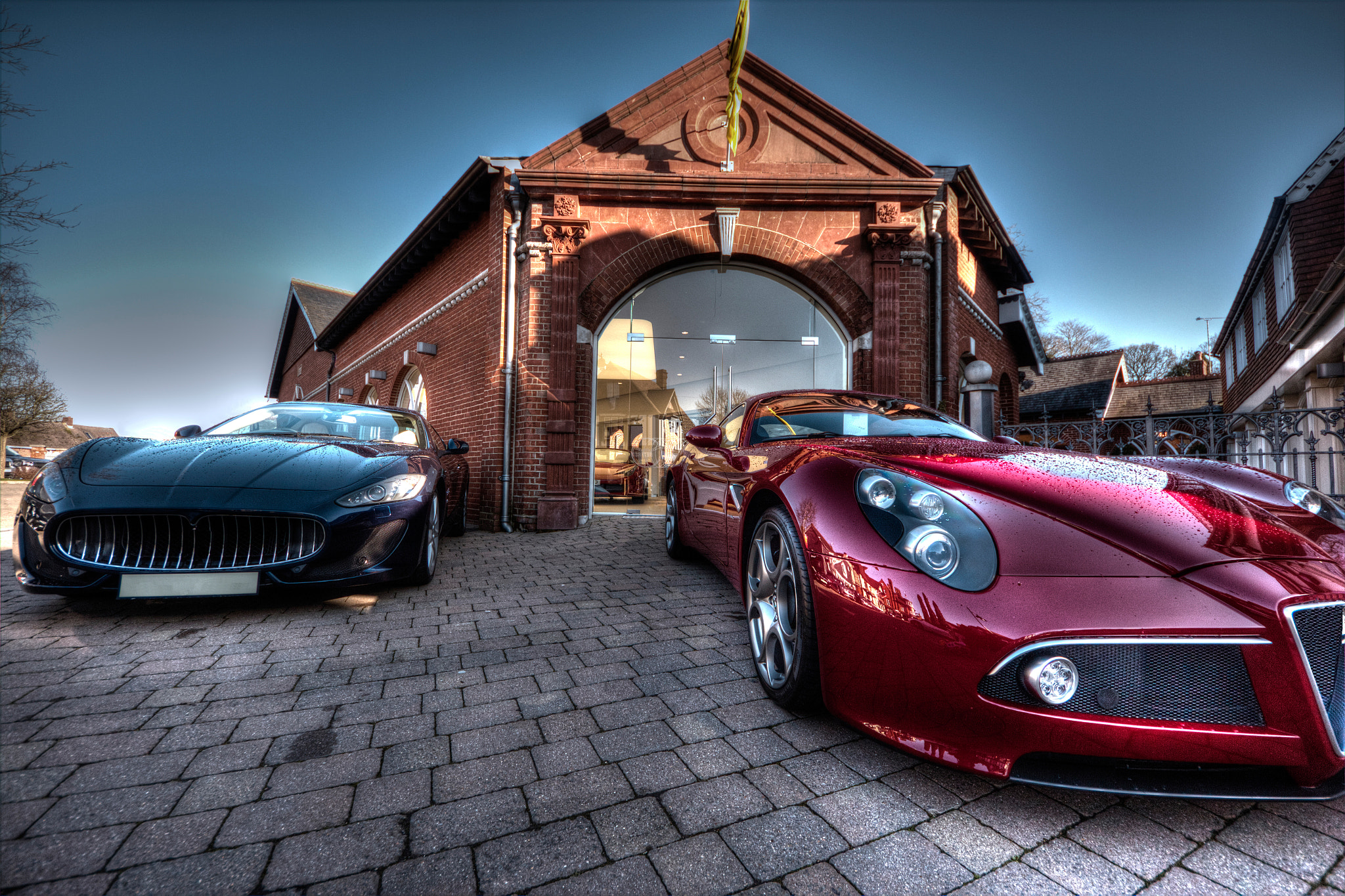 A Maserati and Alfa Romeo parked outside a building