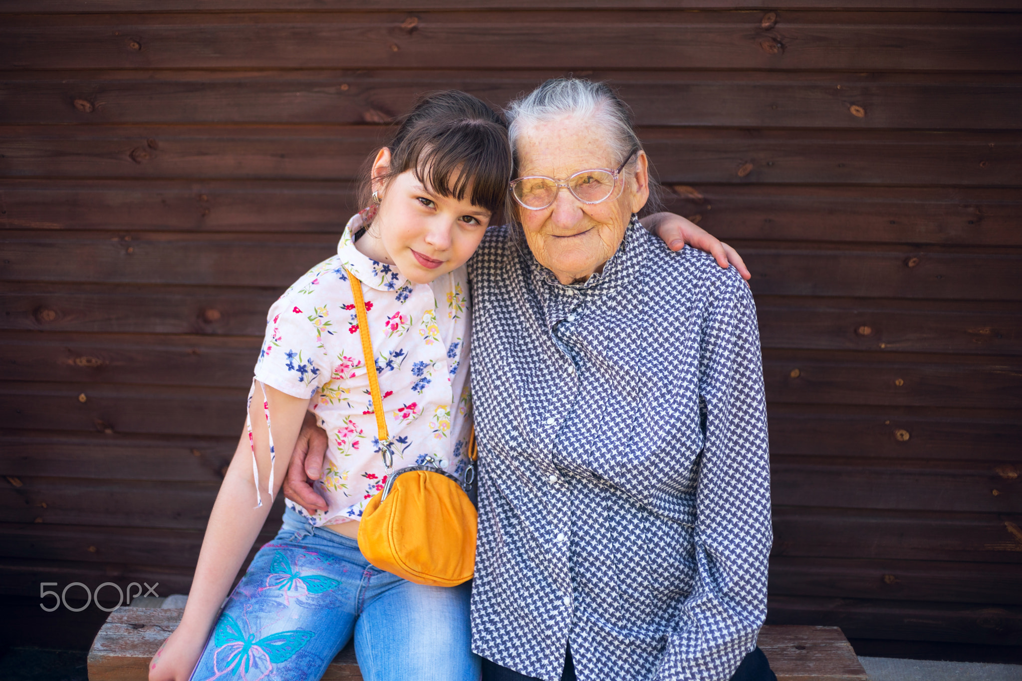 Great-grandmother, and great-granddaughter sitting arm  in arm.