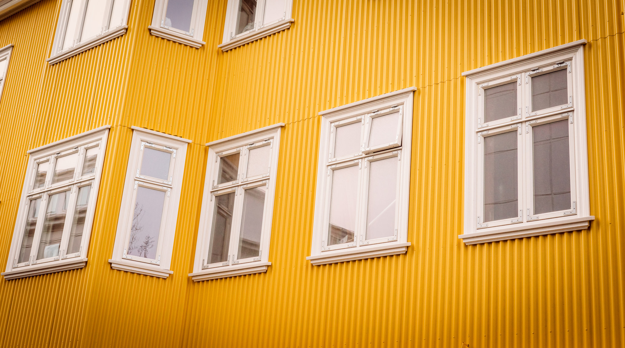 Sony a7R + Sony 50mm F1.4 sample photo. White windows on a yellow facade photography
