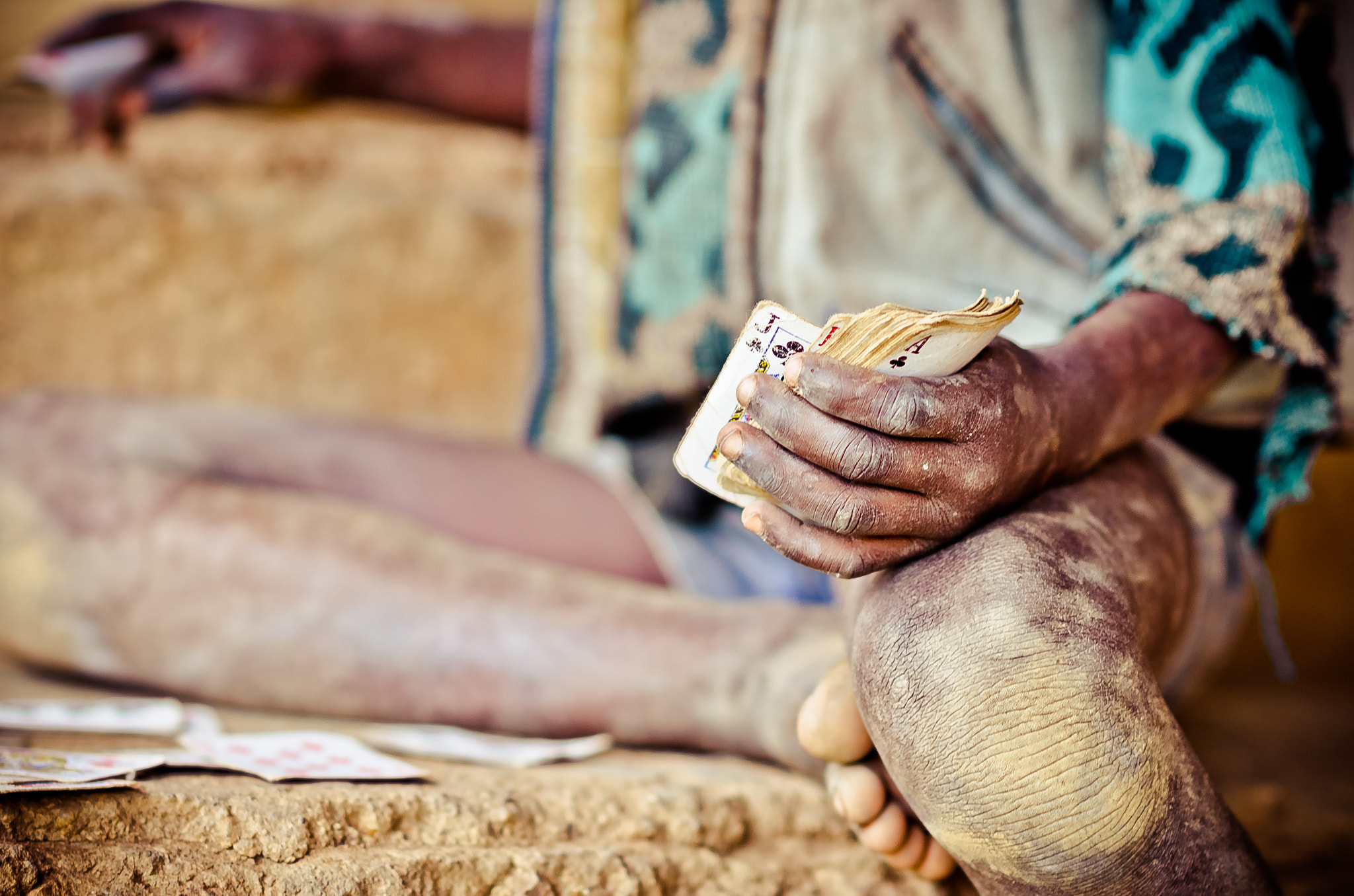 Nikon D7000 + Nikon AF-S Nikkor 85mm F1.4G sample photo. Uganda boy plays cards in the dirt photography