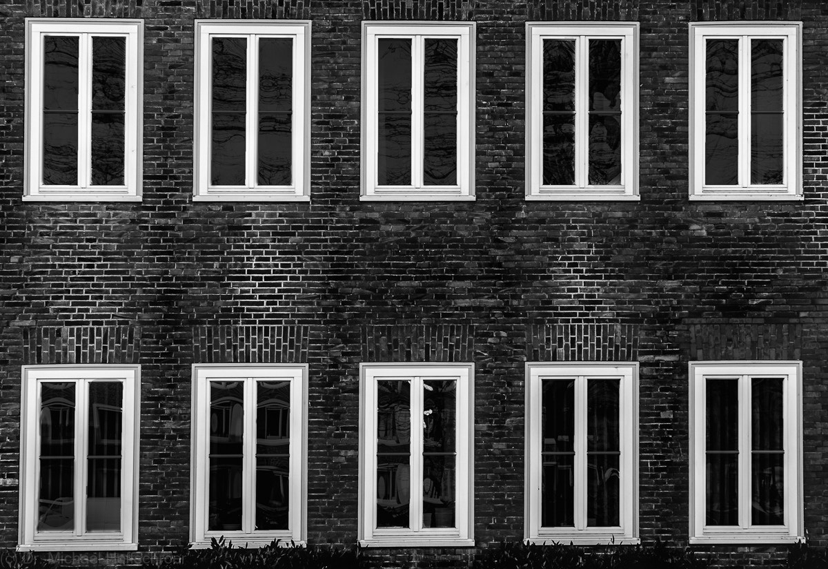Canon EOS 600D (Rebel EOS T3i / EOS Kiss X5) + Canon EF-S 18-55mm F3.5-5.6 sample photo. Symmetric windows in brick wall in black and white photography