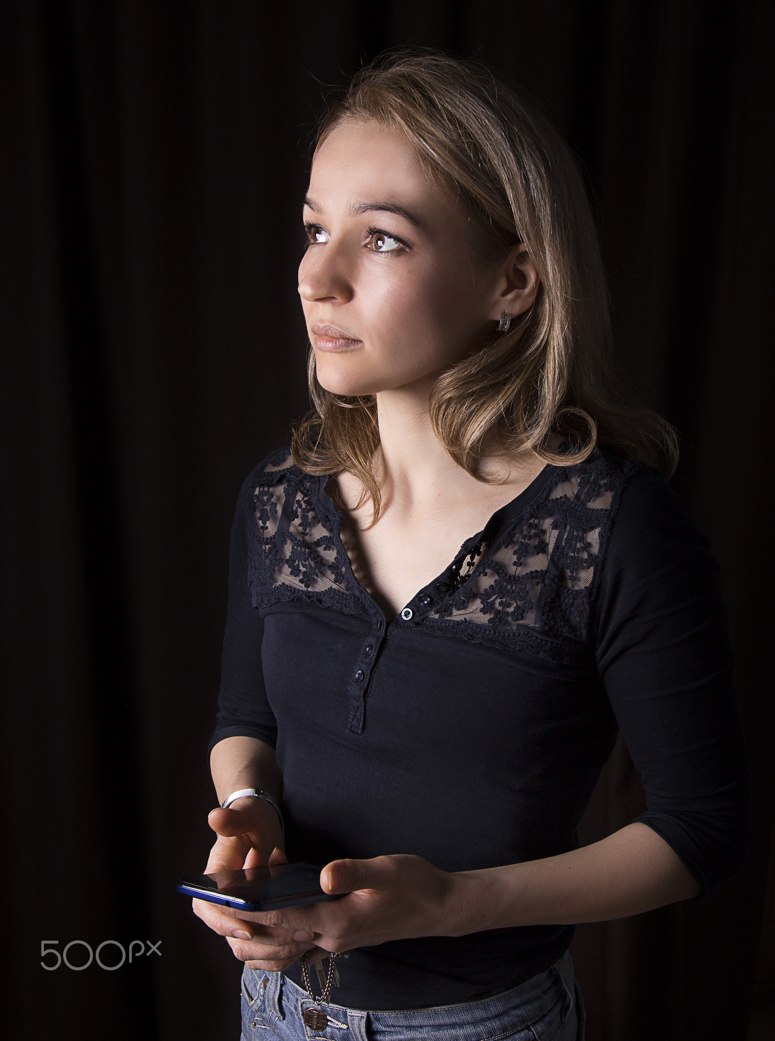 beautiful girl holding a phone in his hand on a dark background