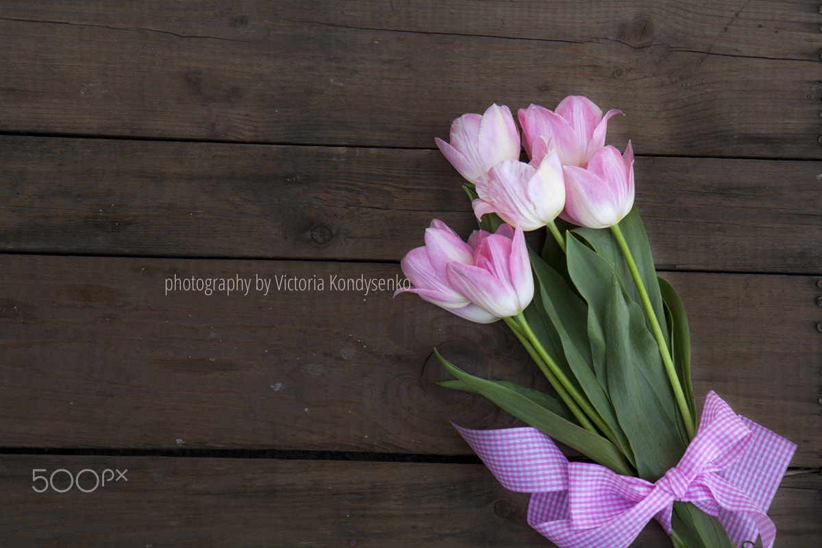 Beautiful bouquet of pink tulips on dark wooden background