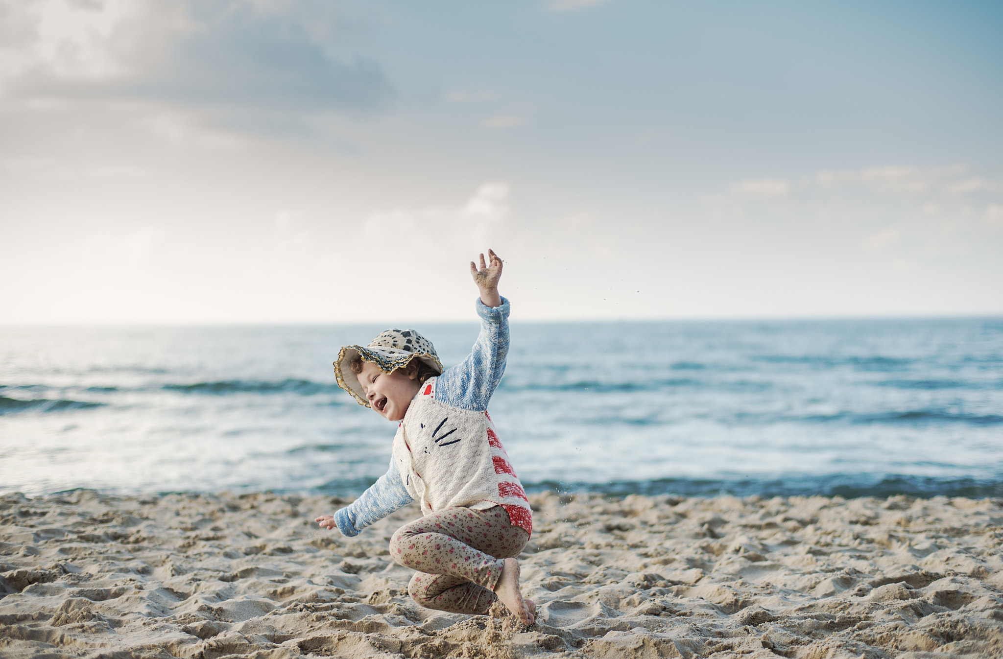 ZEISS Planar T* 50mm F1.4 sample photo. Little girl with a hat jumping and running on the beach photography