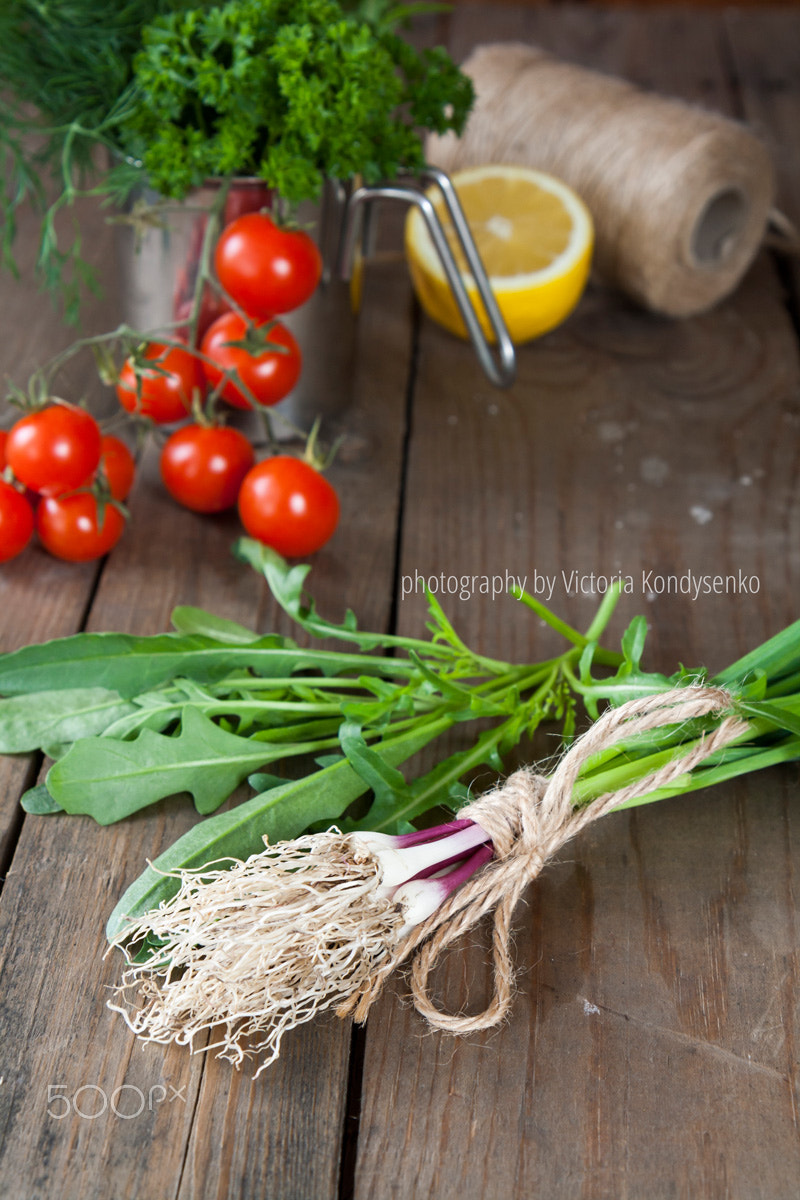 Canon EOS 1000D (EOS Digital Rebel XS / EOS Kiss F) sample photo. Fresh green garlic spears and arugula on wooden table with tomat photography