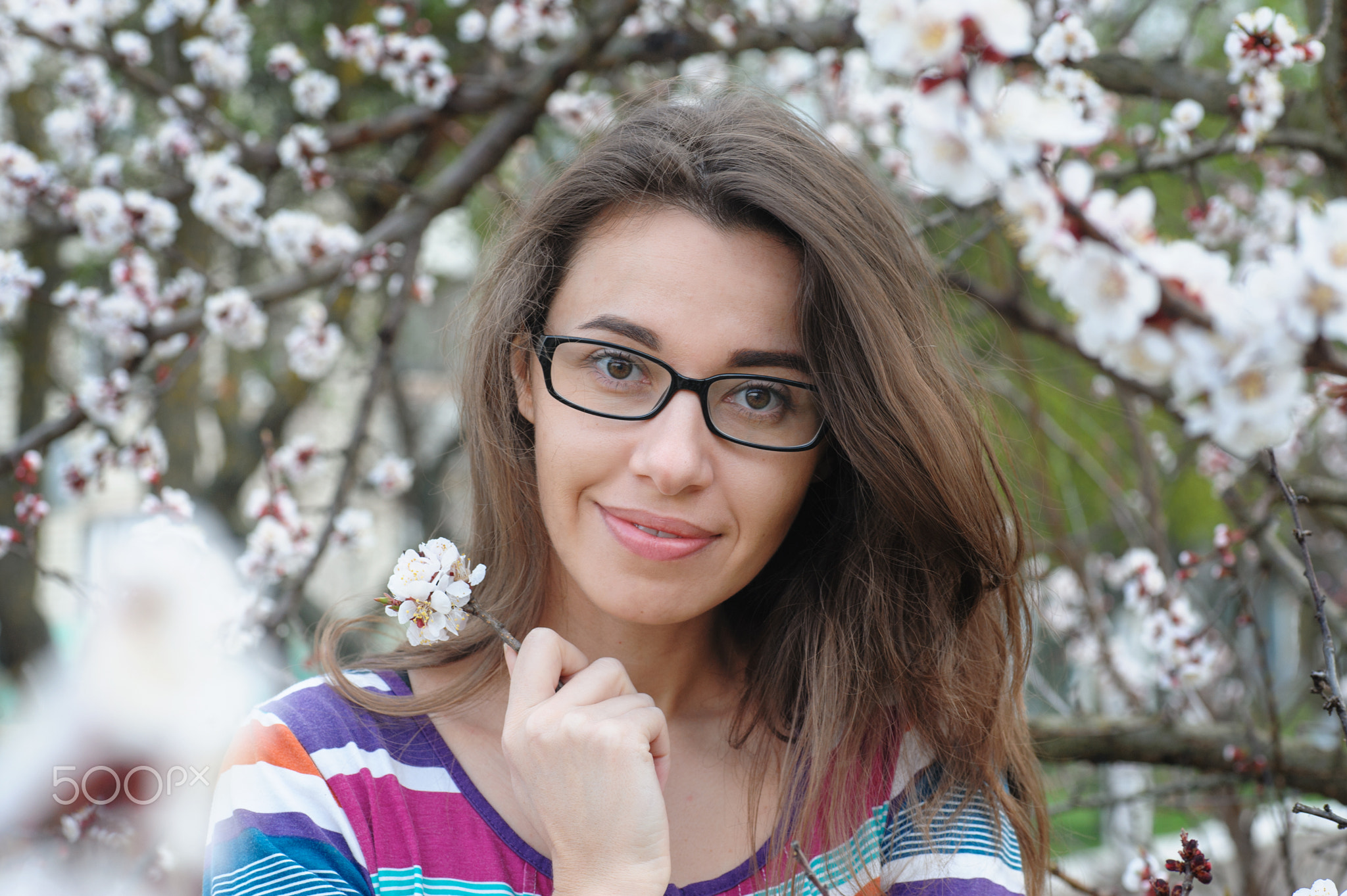 portrait of smiling caucasian brunette woman in spring blossom garden