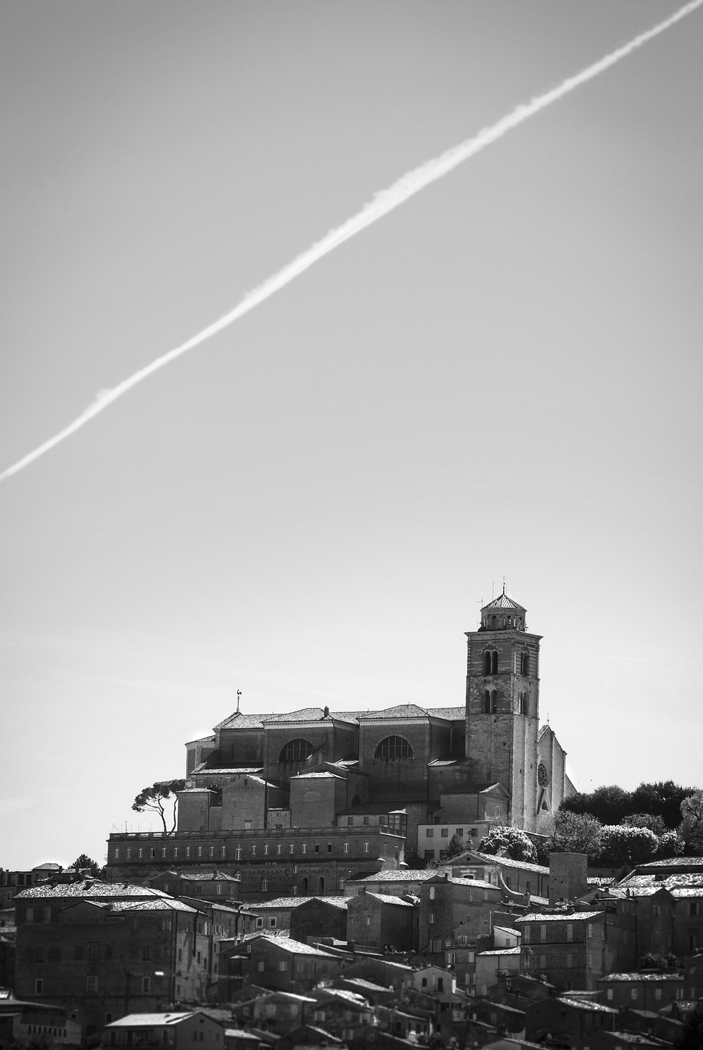 Nikon 1 Nikkor VR 30-110mm F3.8-5.6 sample photo. Medieval village in the hills with a bell tower, airplane trail photography