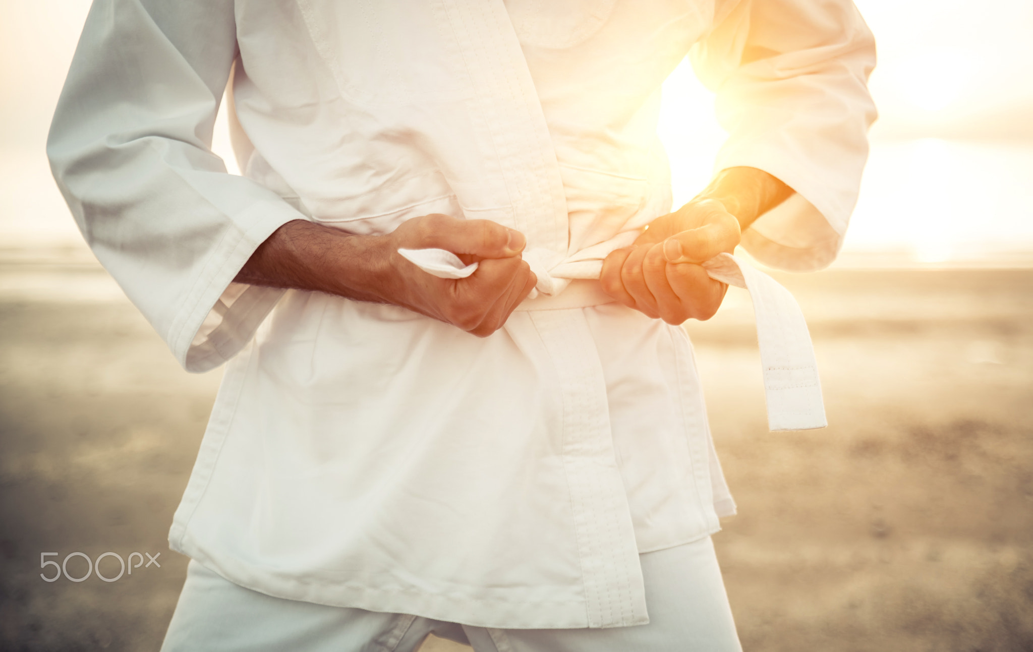 Karate fighter tying his kimono belt up