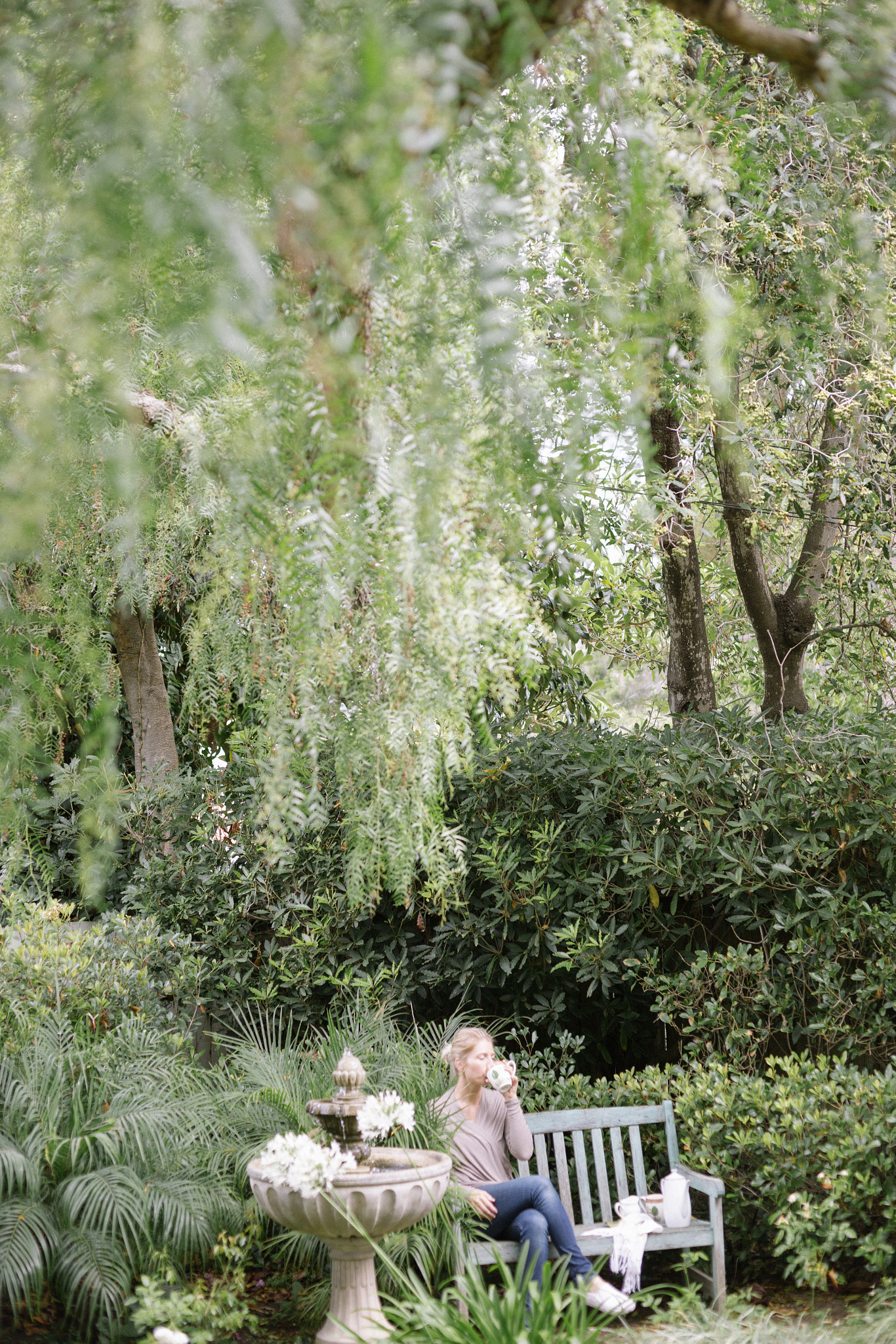 Woman sitting on a wooden bench in a garden, taking a break.