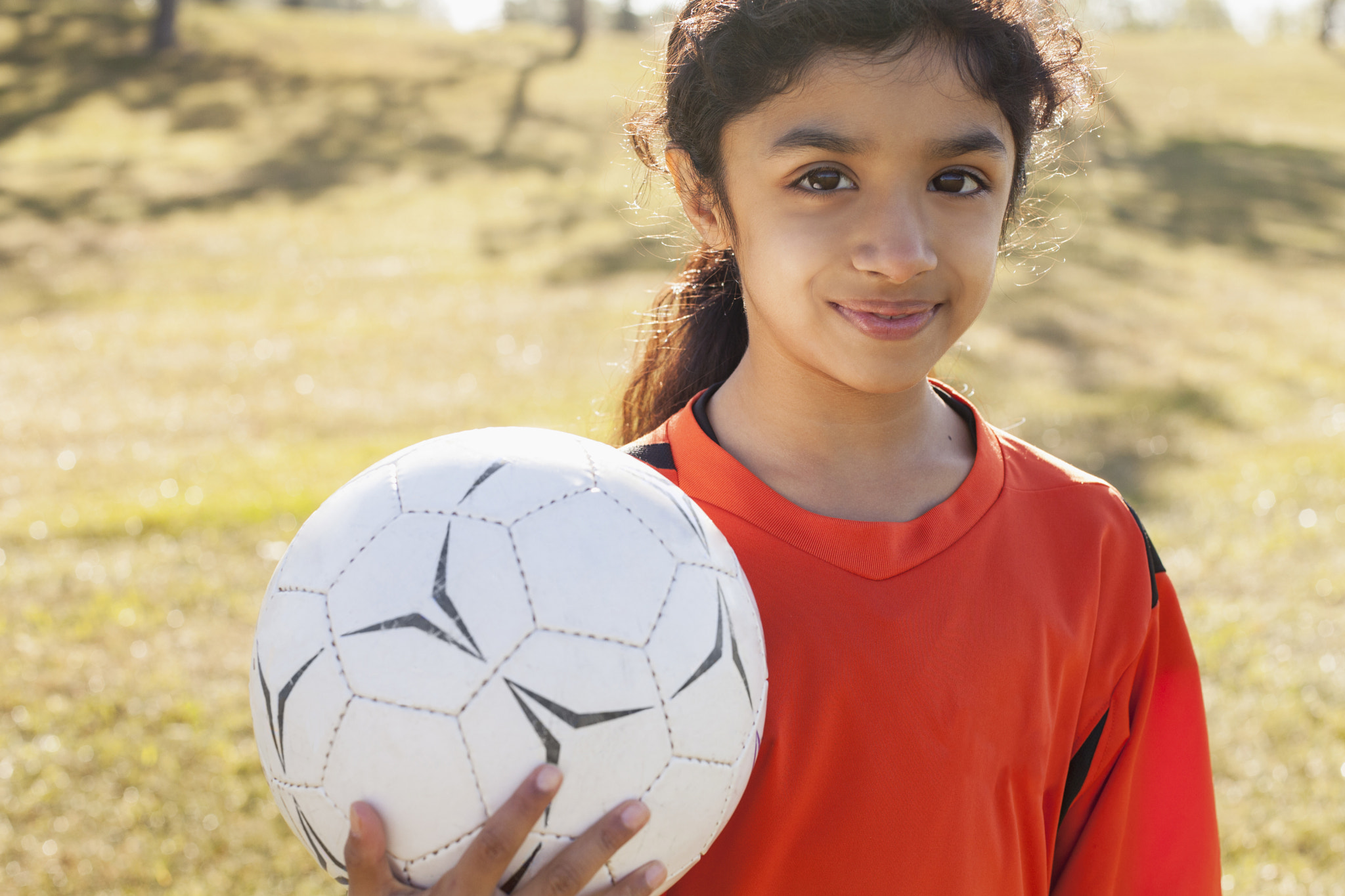 Girl soccer player holding soccerball.
