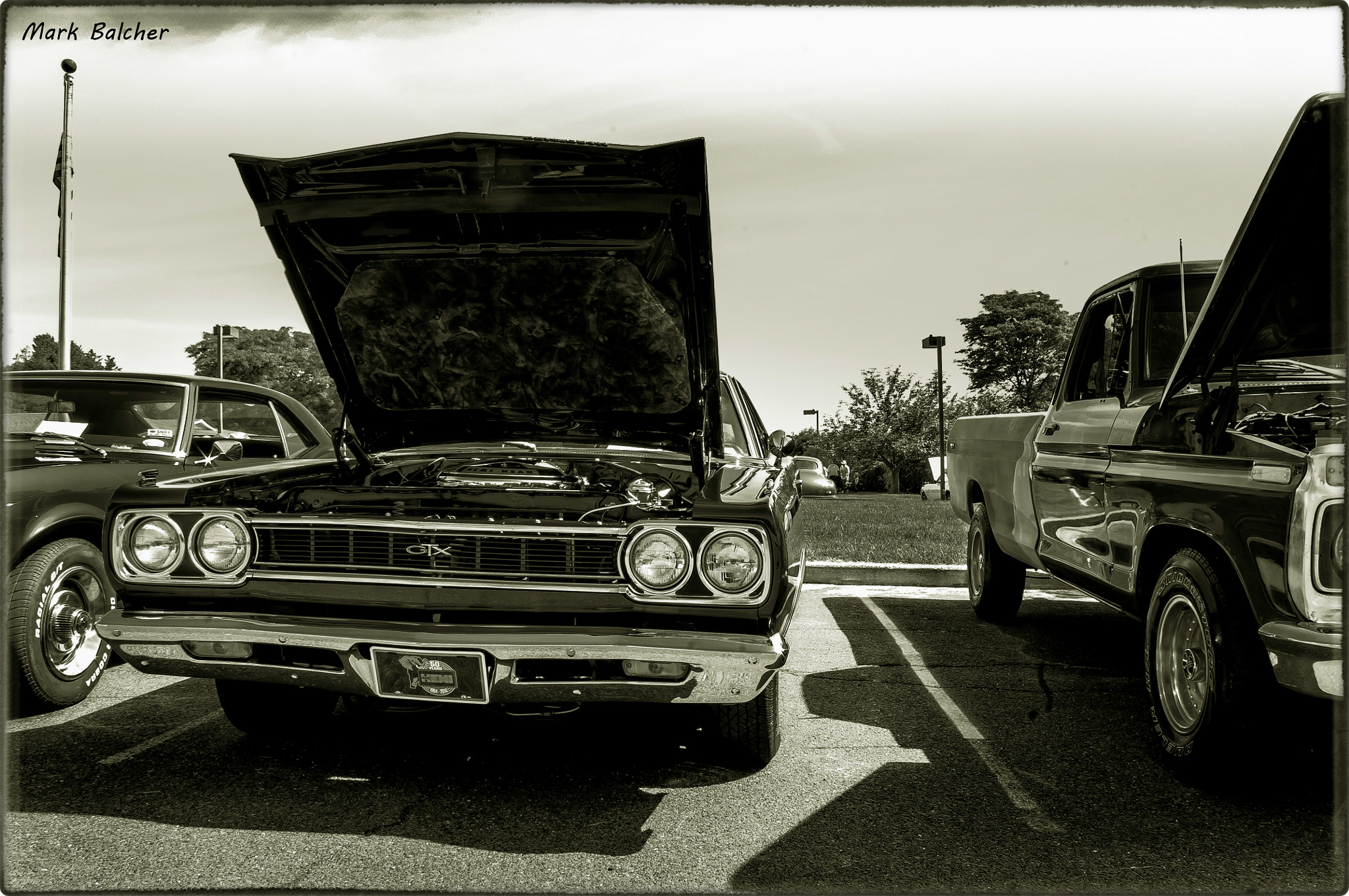 Pentax K-x + Pentax smc DA 18-55mm F3.5-5.6 AL sample photo. A black and white shot of the plymouth gtx, with it's hood up and a ford pick up next to it. photography