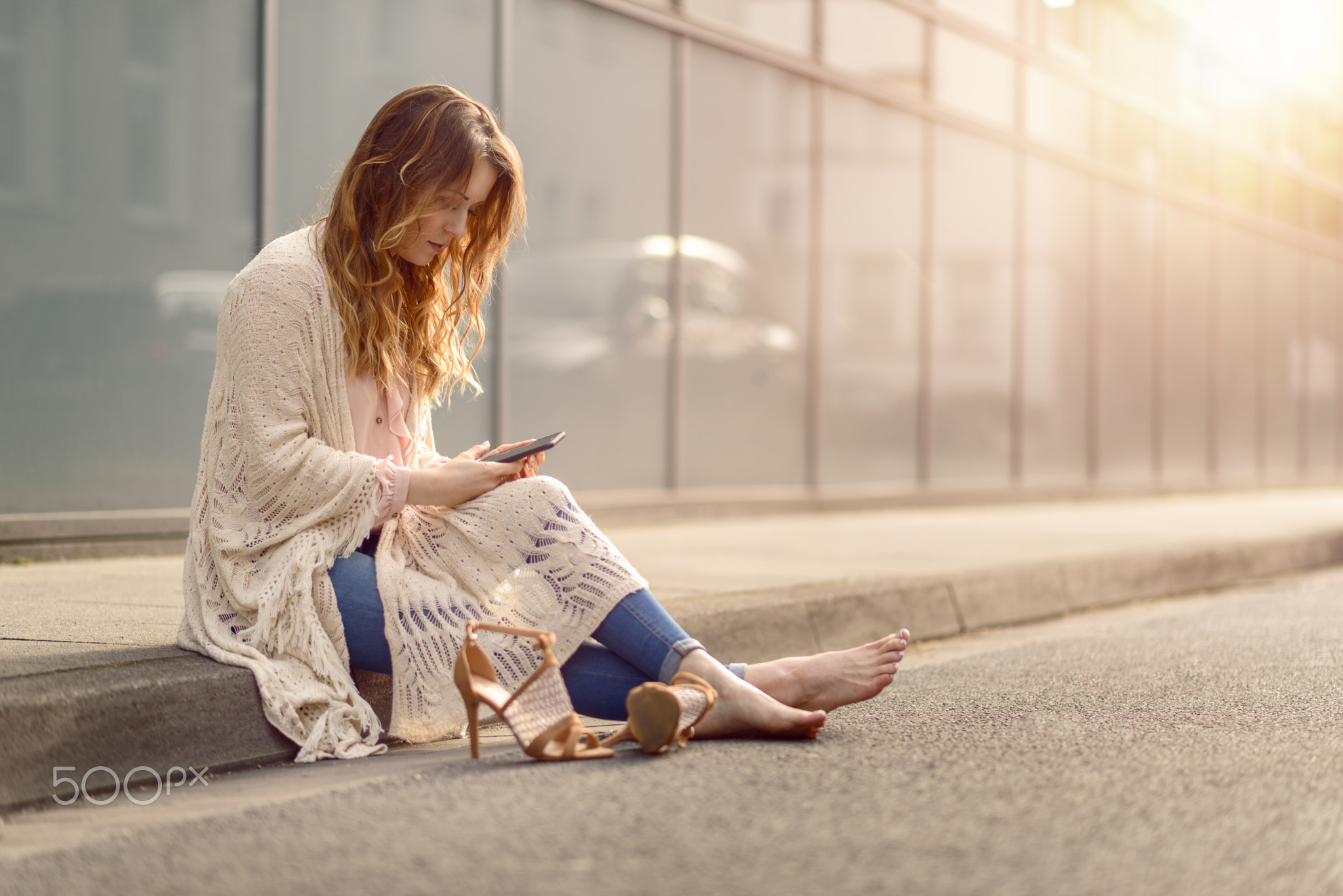 Attractive woman sitting on the kerb of a street