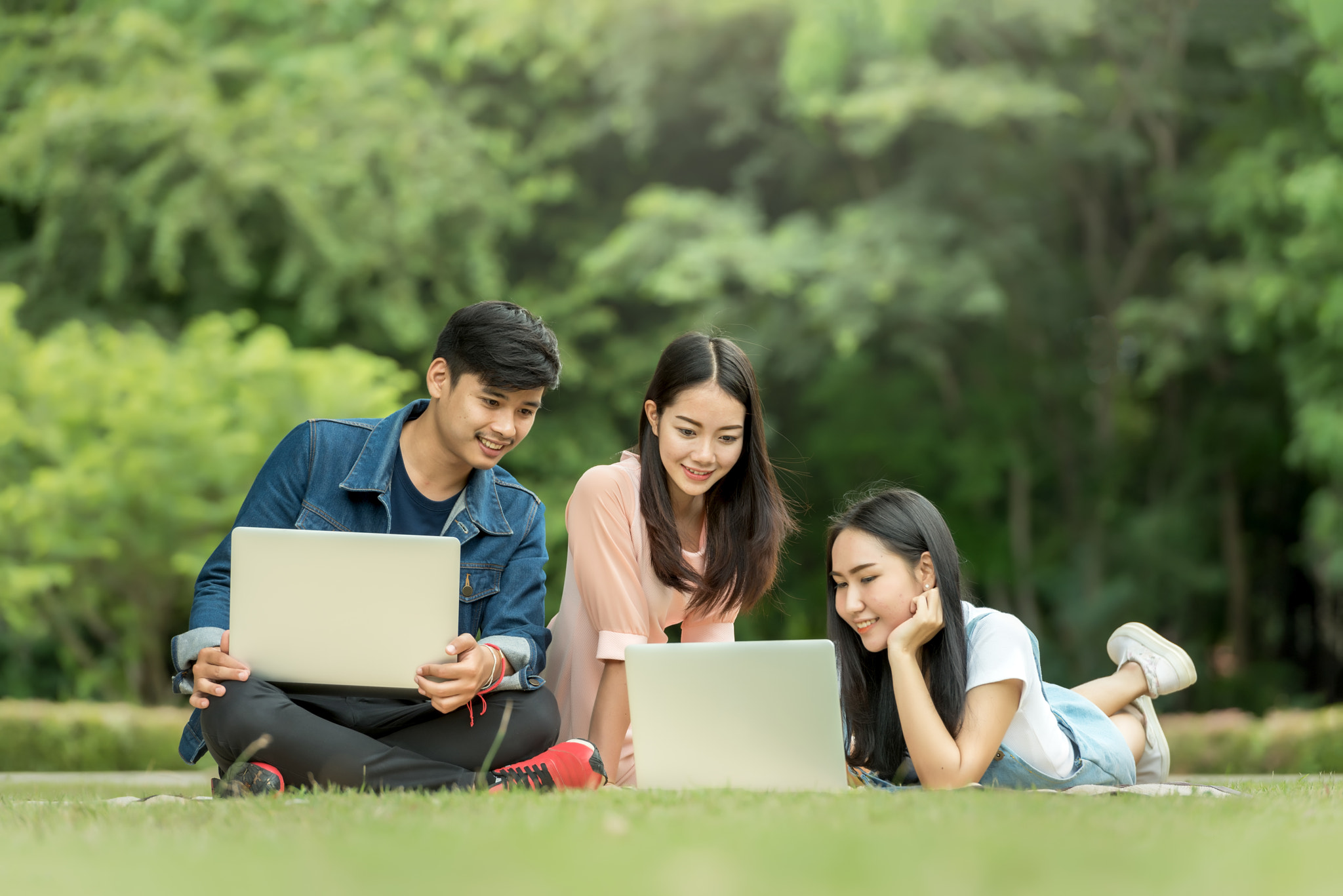 Young student using laptop together in the park