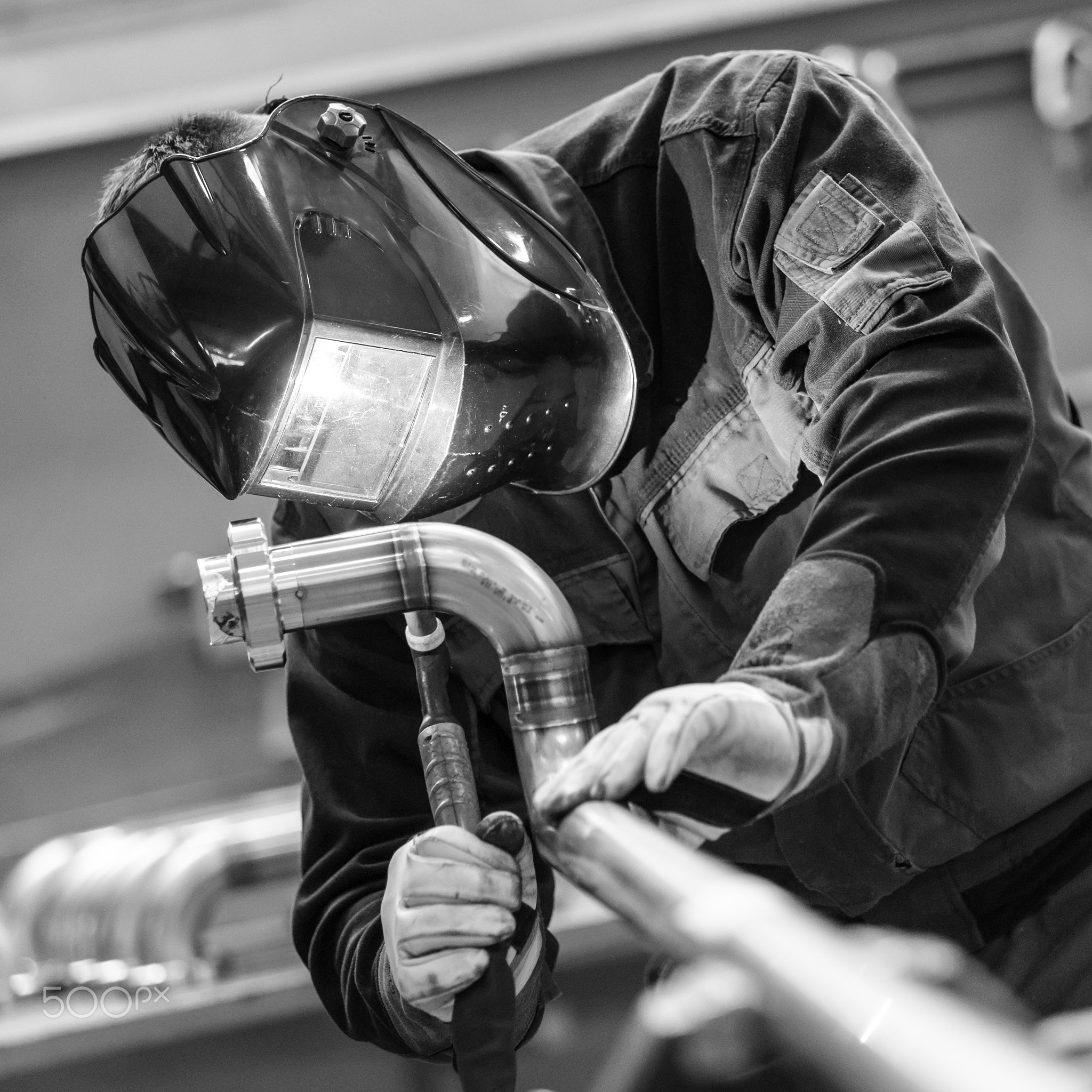 Industrial worker welding in metal factory.