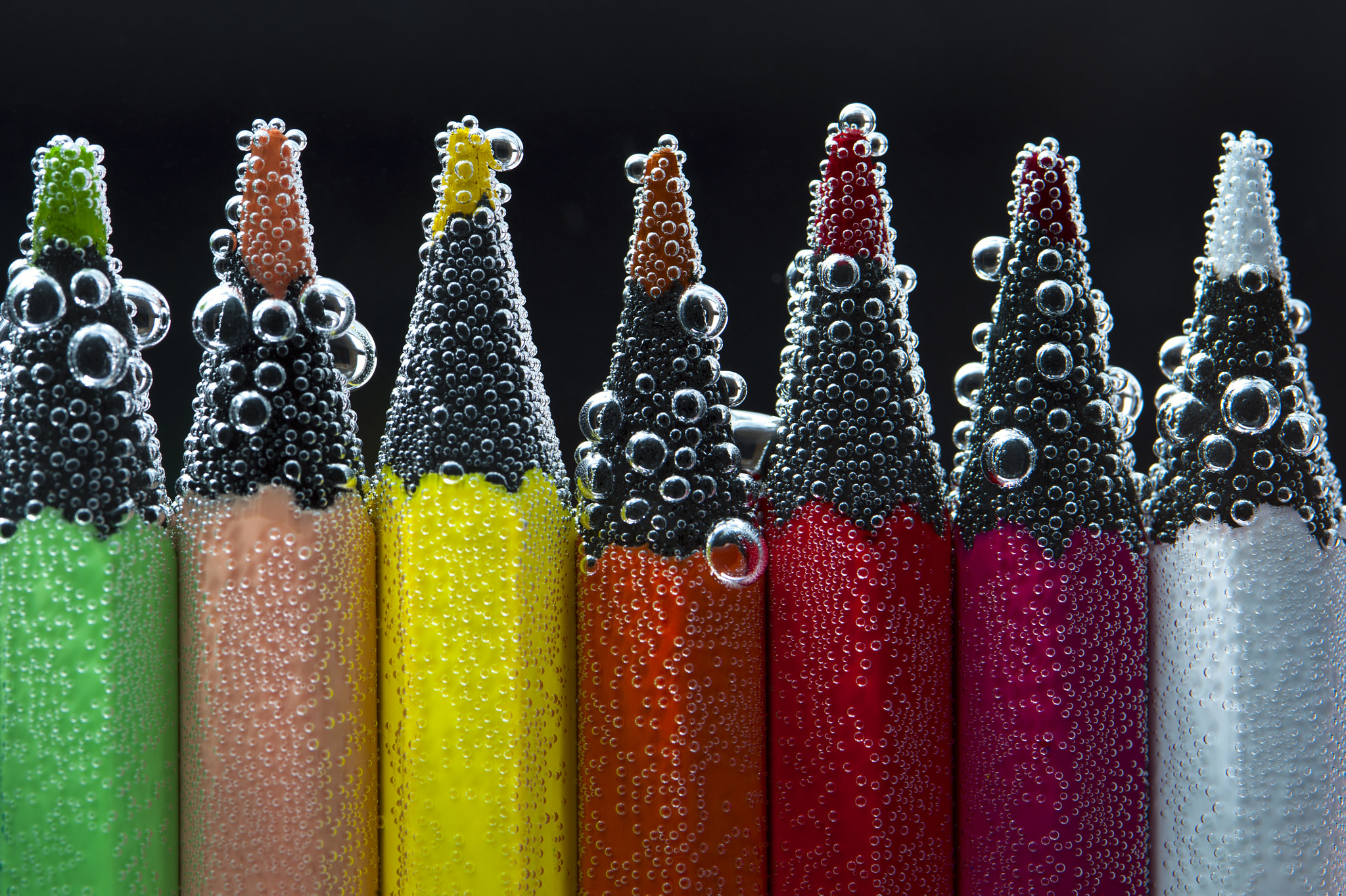 Bright pencils in water with bubbles
