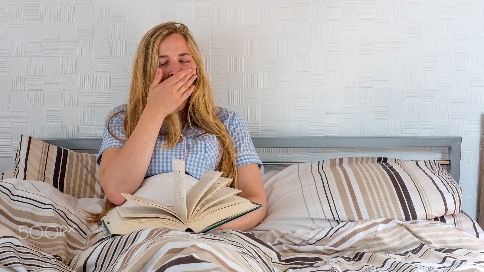 Panasonic Lumix DMC-GH4 + Panasonic Leica DG Summilux 25mm F1.4 II ASPH sample photo. Pretty girl yawns while reading book as she rests in bed photography