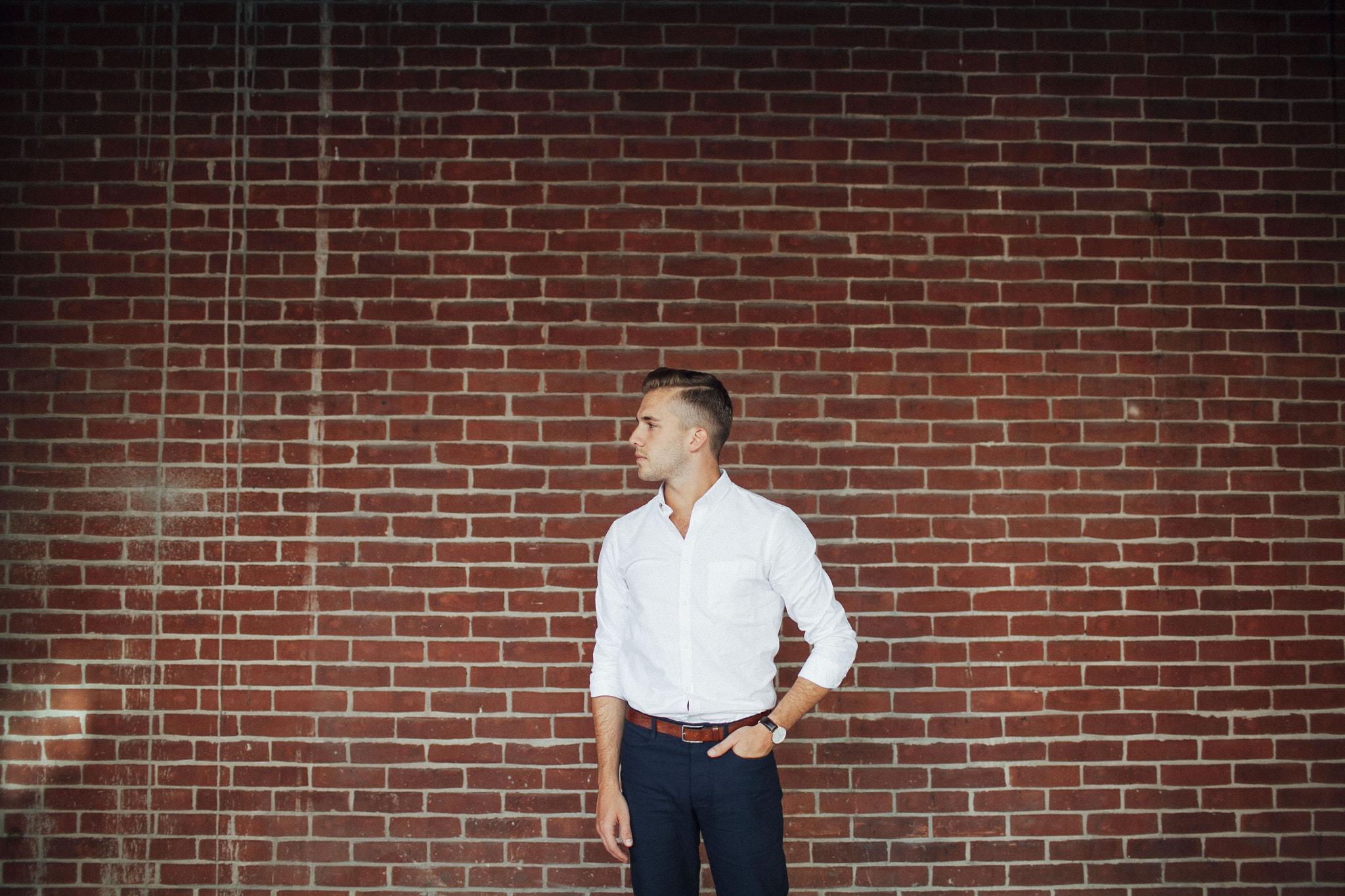 Young man looking ambiguous on in front of brick wall