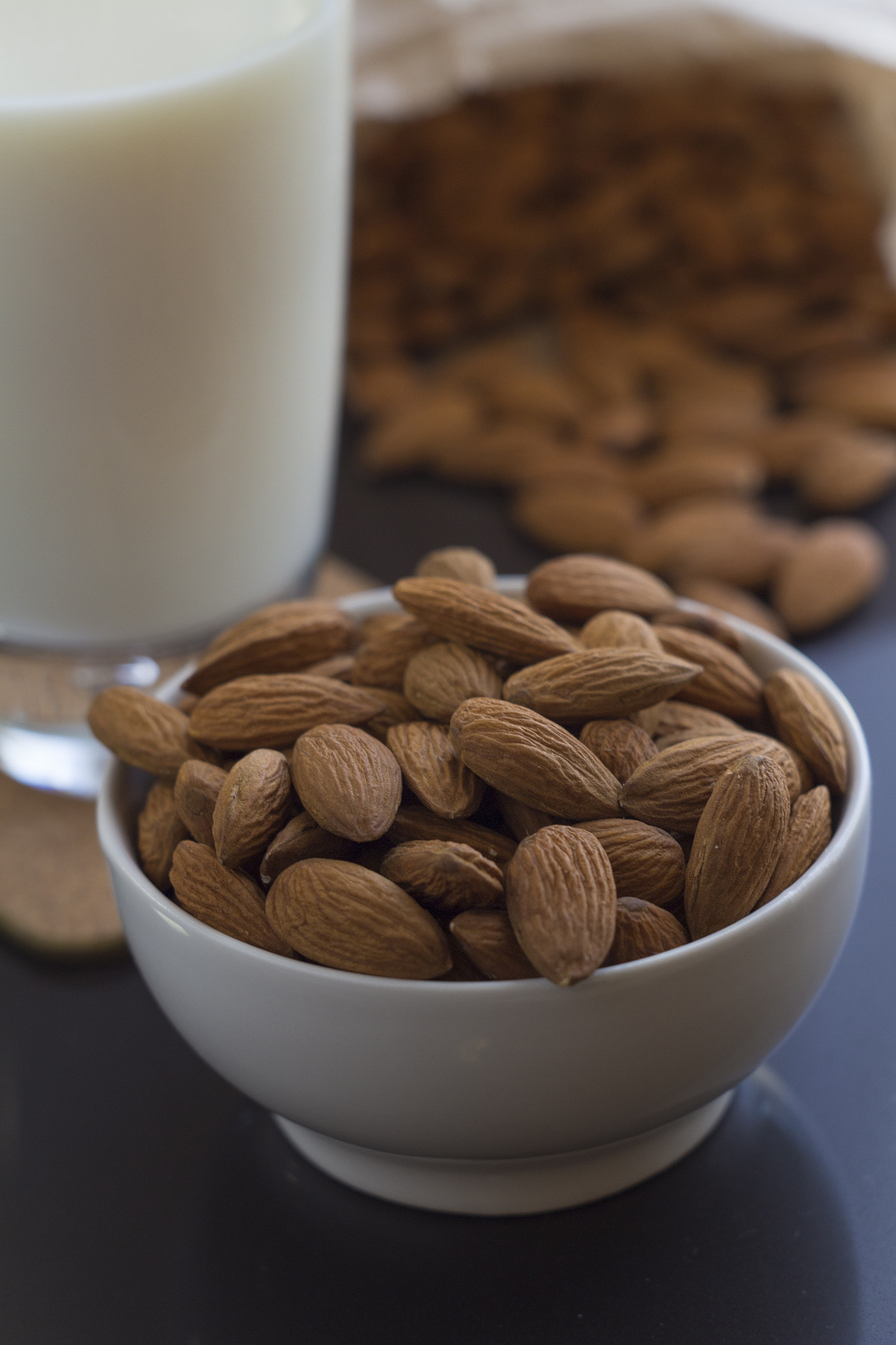 Canon EF 35-80mm f/4-5.6 sample photo. Vegan almond milk with organic almonds on black marble table photography