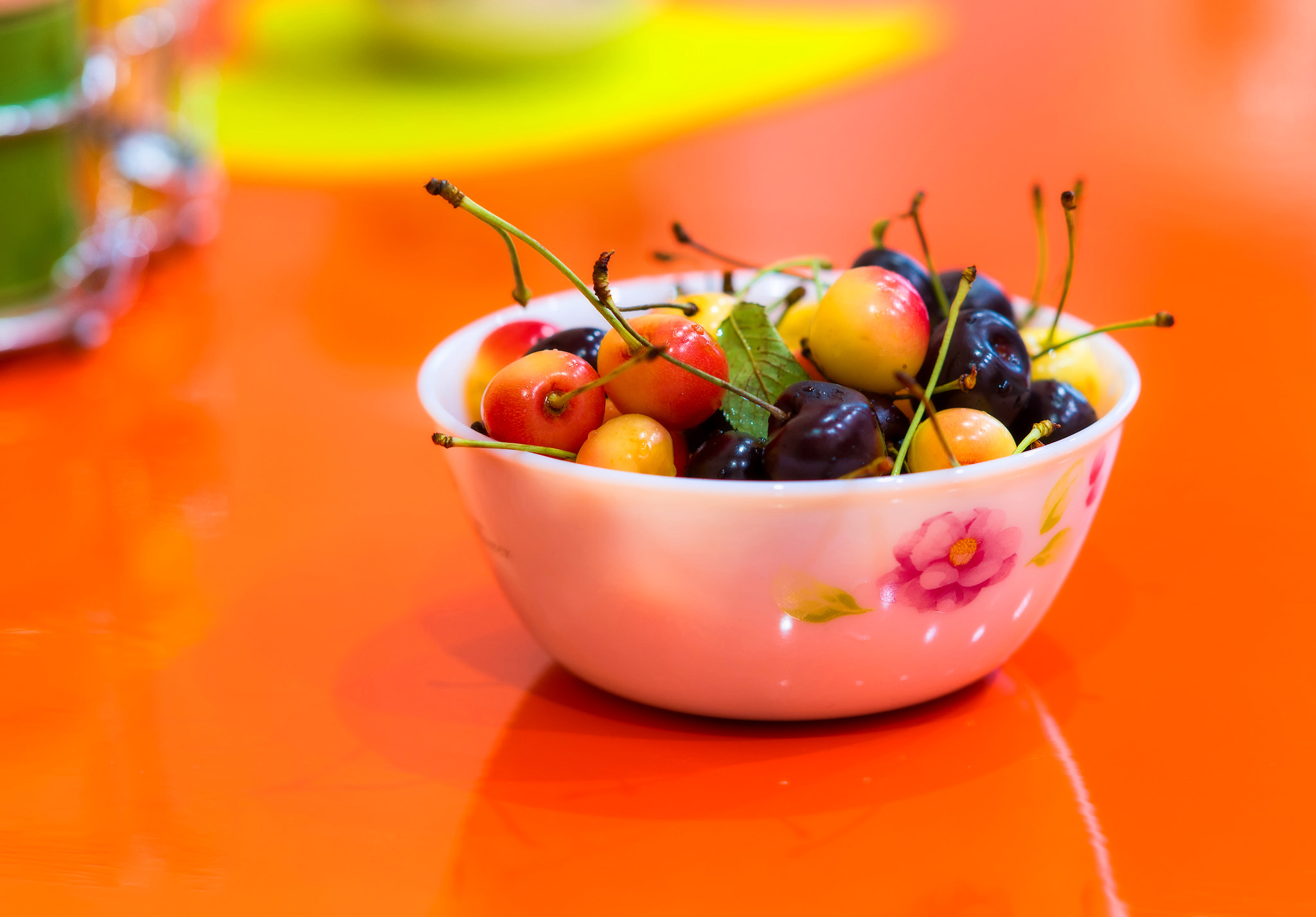 Sony Sonnar T* 135mm F1.8 ZA sample photo. A bowl of fresh cherries on orange table. photography