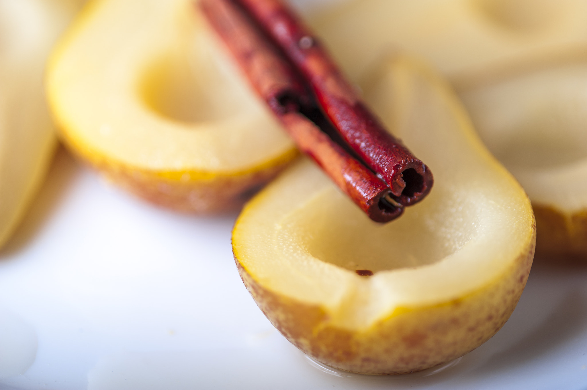 Nikon D700 + AF Micro-Nikkor 105mm f/2.8 sample photo. Closeup of pears cooked in sugar syrup with cinnamon stick on white plate photography