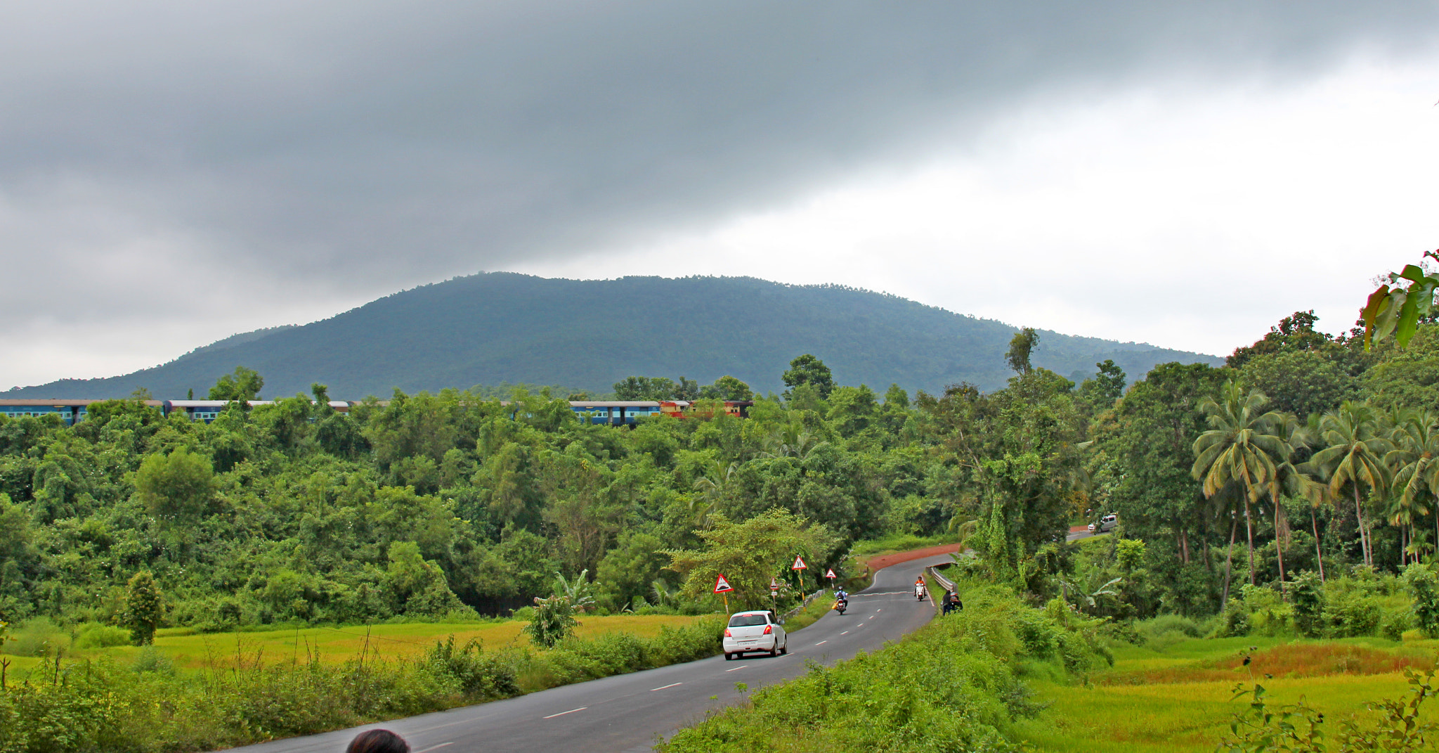 Canon EF 28-135mm F3.5-5.6 IS USM sample photo. Nice combination of cloud moutain train jungle tar road and rice field rice in goa india photography