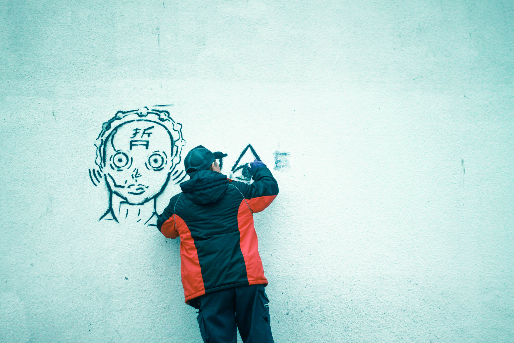 Canon EOS 500D (EOS Rebel T1i / EOS Kiss X3) + Canon EF 50mm F1.8 II sample photo. A man cleaning a grafitti on a a wall. photography