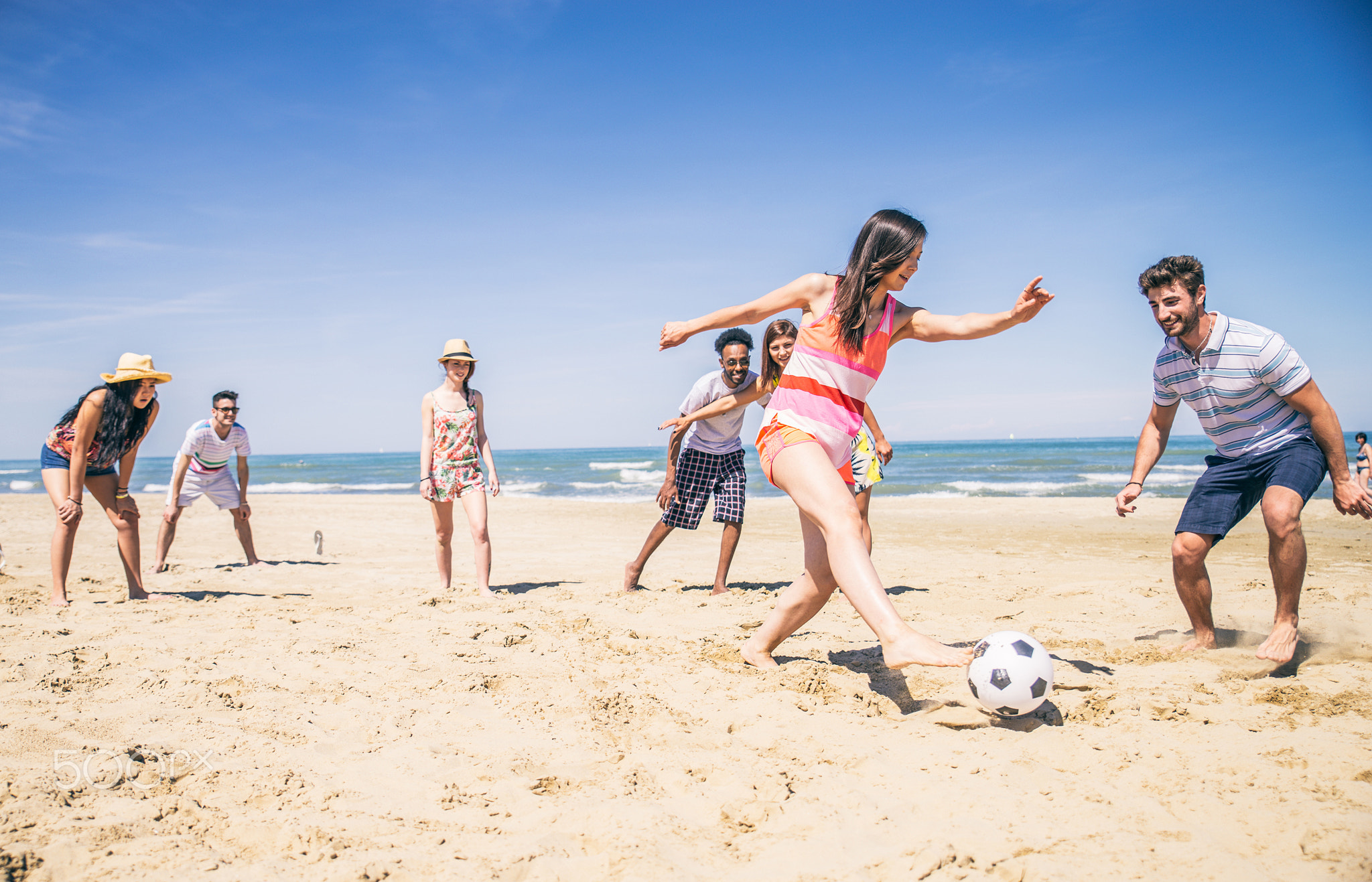 Friends playing football on the beach