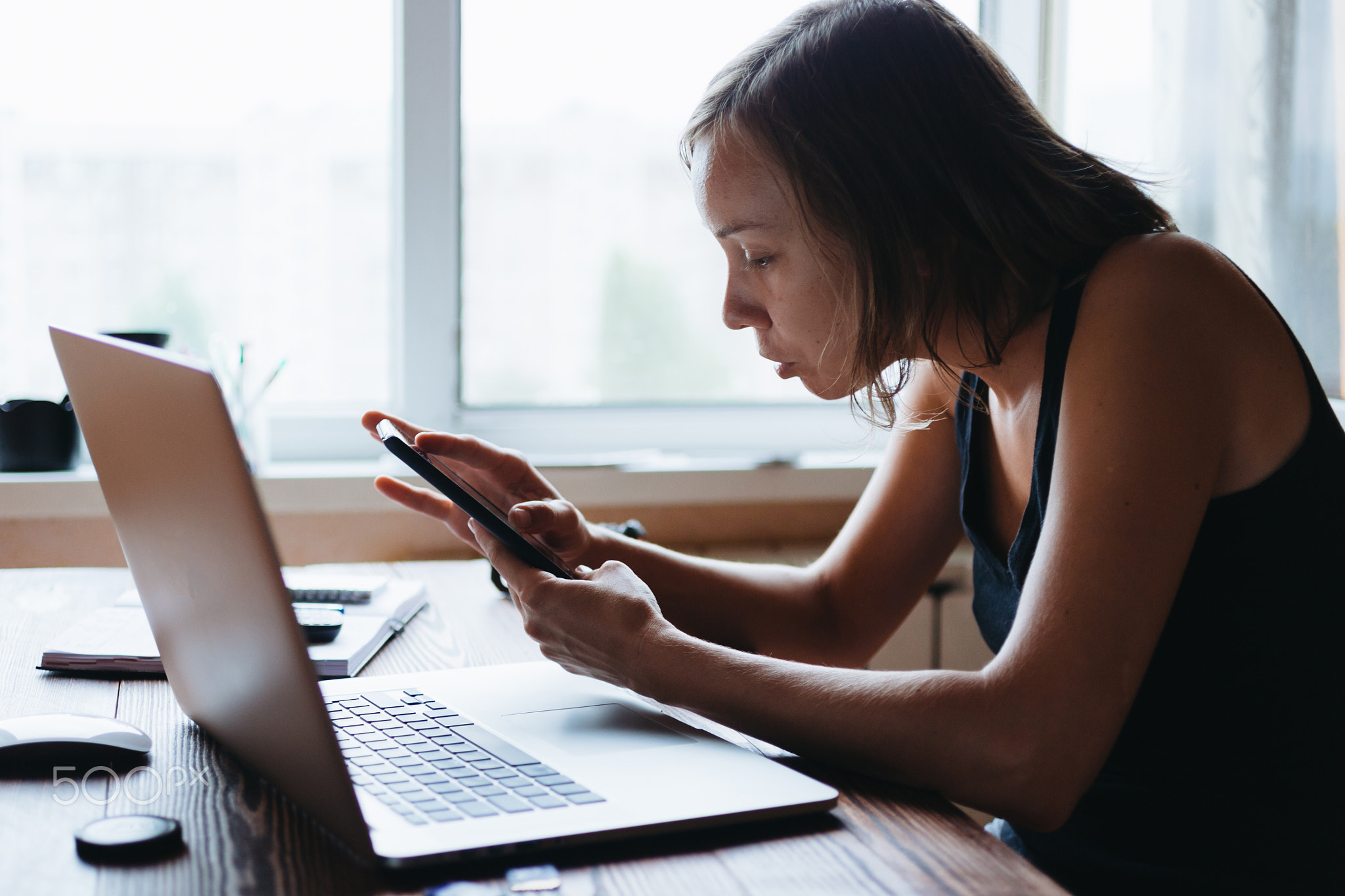 Woman working on computer and looking at the phone