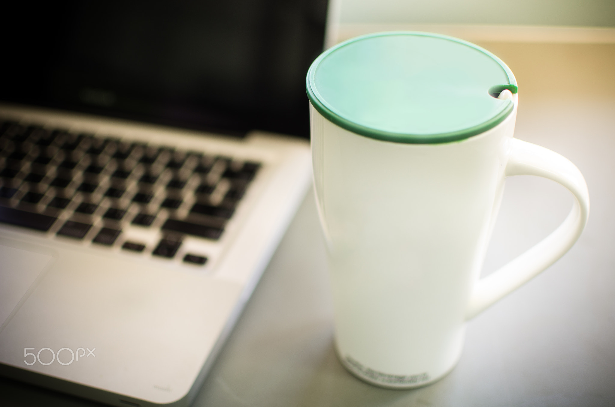 Vintage style of coffee cub with blurred laptop.