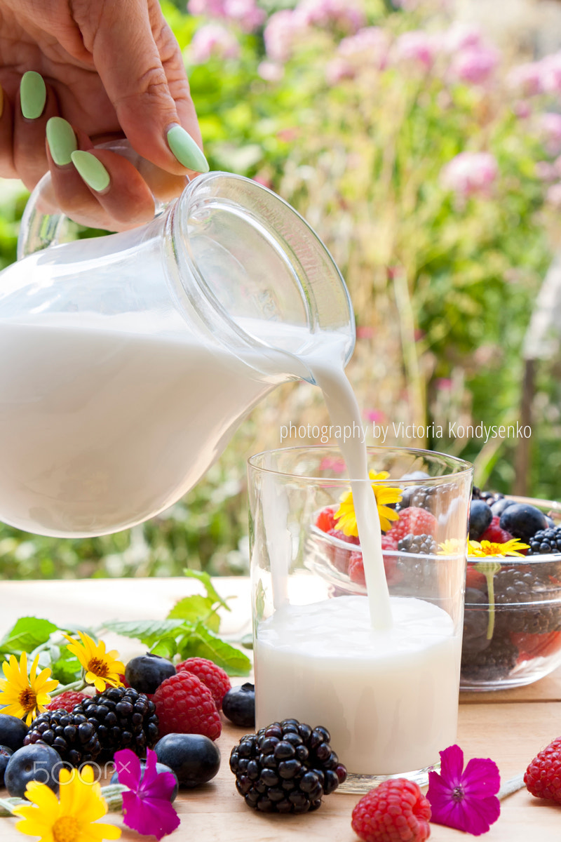 Canon EOS 1000D (EOS Digital Rebel XS / EOS Kiss F) sample photo. Pouring milk in the glass on the table with summer berries photography