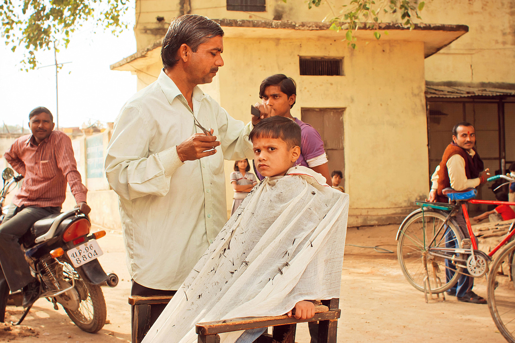 Canon EOS 40D + Canon EF 28mm F1.8 USM sample photo. Kid in the outdoor hairdresser shop in india photography