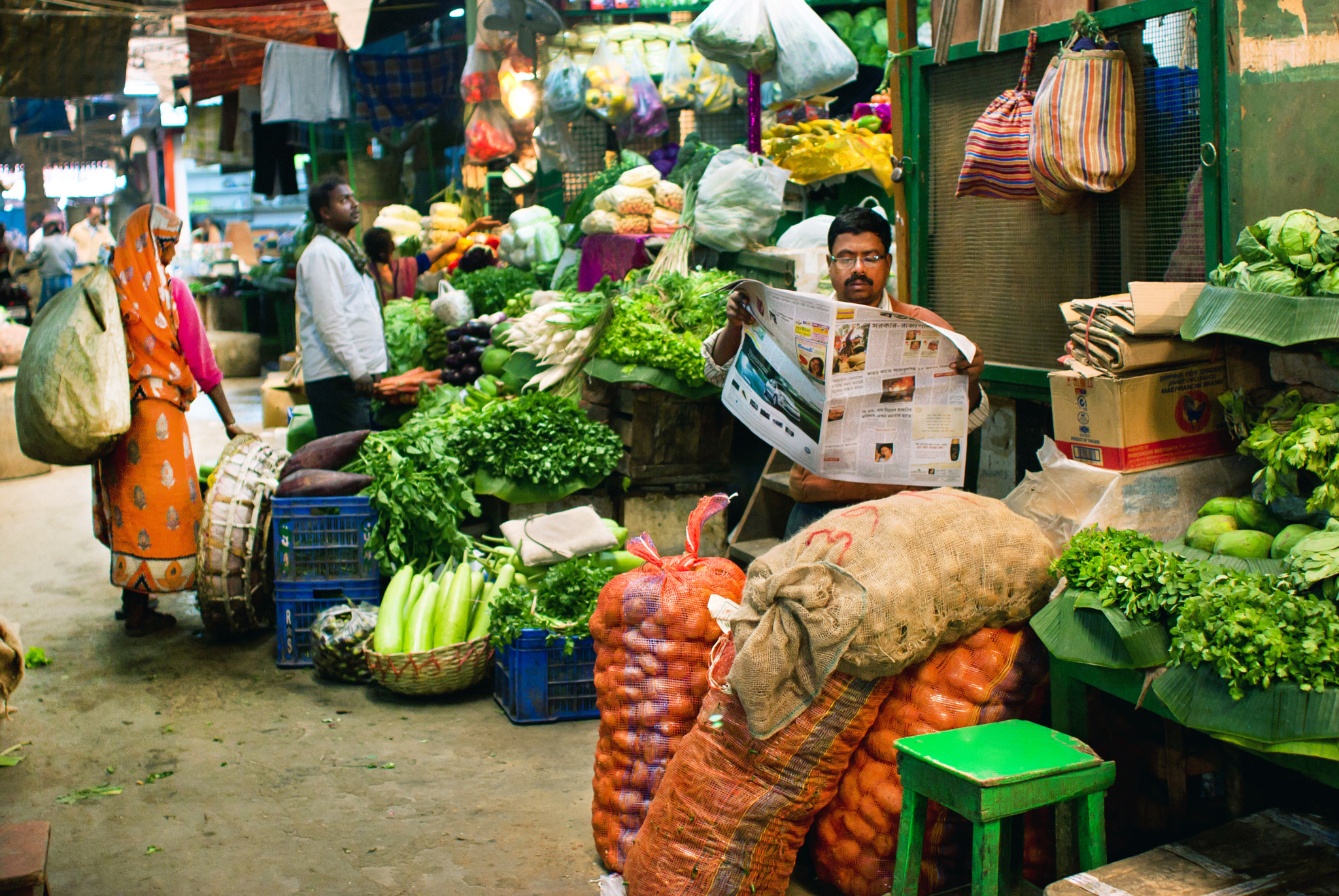 Canon EOS 40D + Canon EF 28mm F1.8 USM sample photo. Vegetable seller reads a newspaper photography