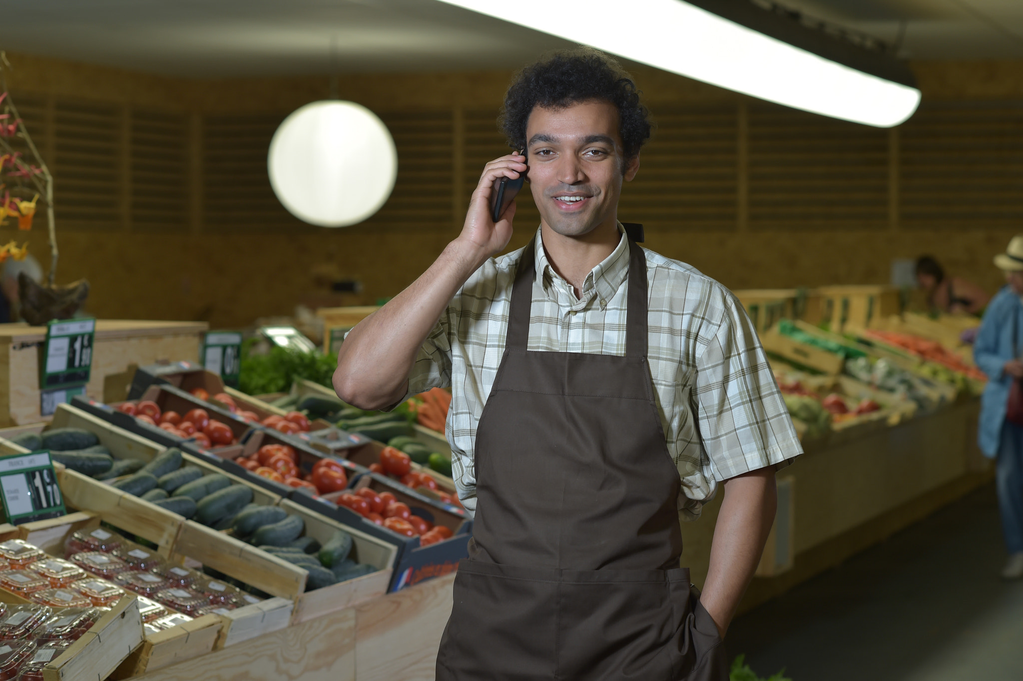 Nikon D4S + Nikon AF-S Nikkor 85mm F1.4G sample photo. Grocery clerk phoning in produce aisle of supermarket store photography
