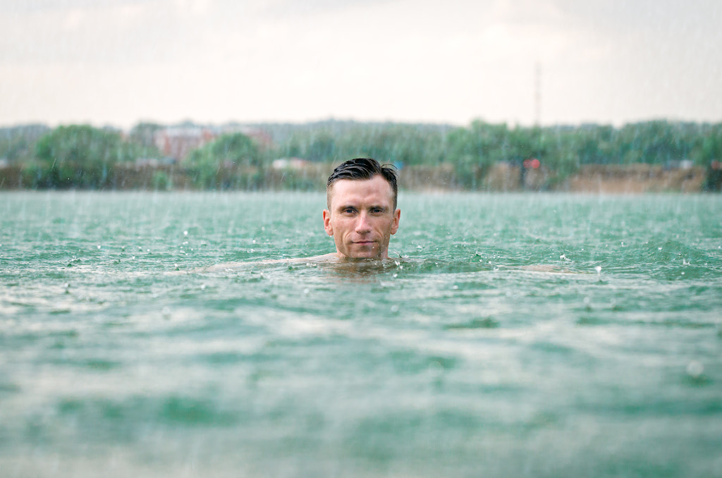 Man swimming in lake under the rain in thunderstorm by Bogomyakov Sergey on 500px.com