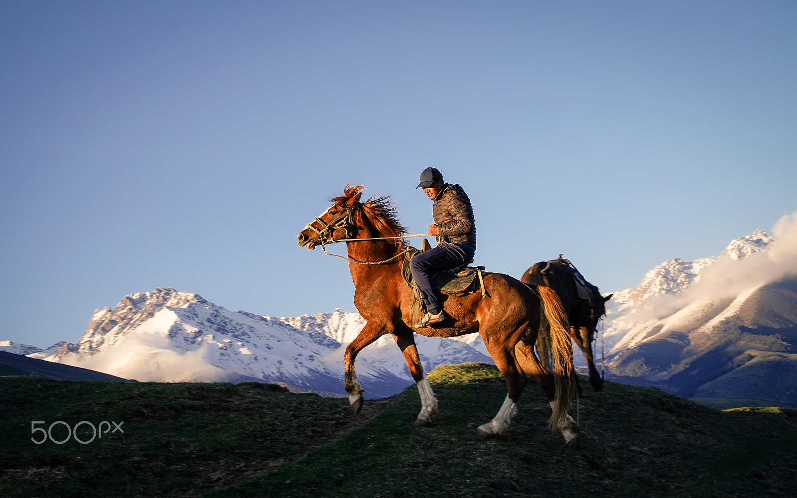 Sony a7R + Sony E PZ 18-200mm F3.5-6.3 OSS sample photo. Man on a horse on a background of snow-capped moun photography