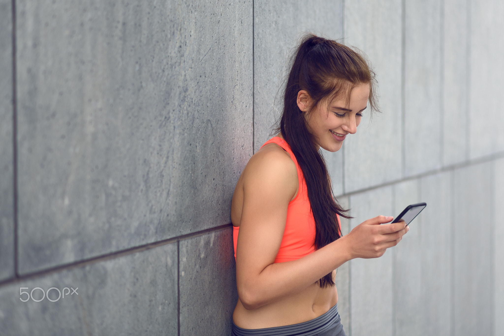 Sporty young woman standing checking her messages